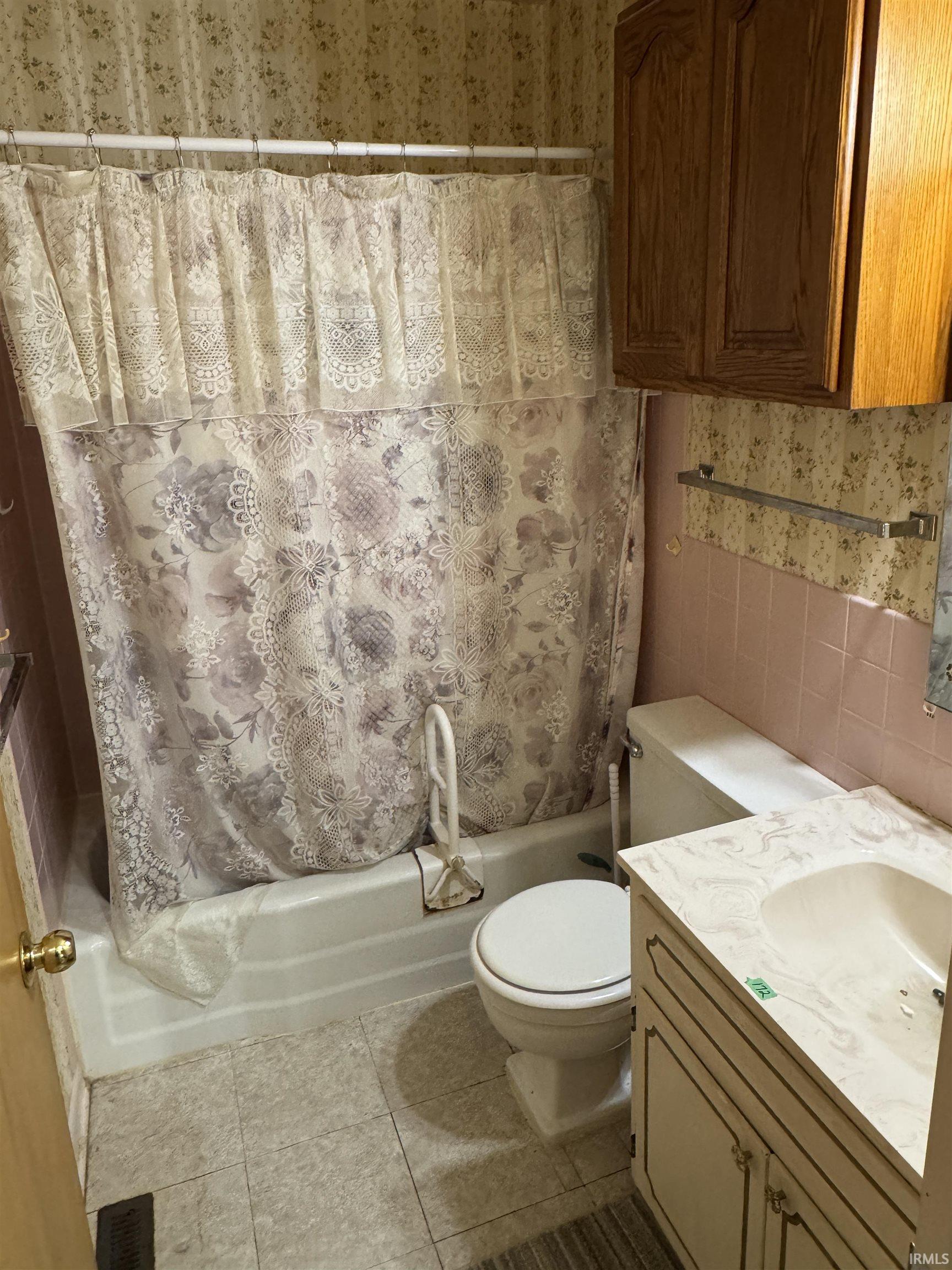 Bathroom featuring a built-in tub with shower, single vanity with integrated sink, toilet, and wood-finish wall cabinetry