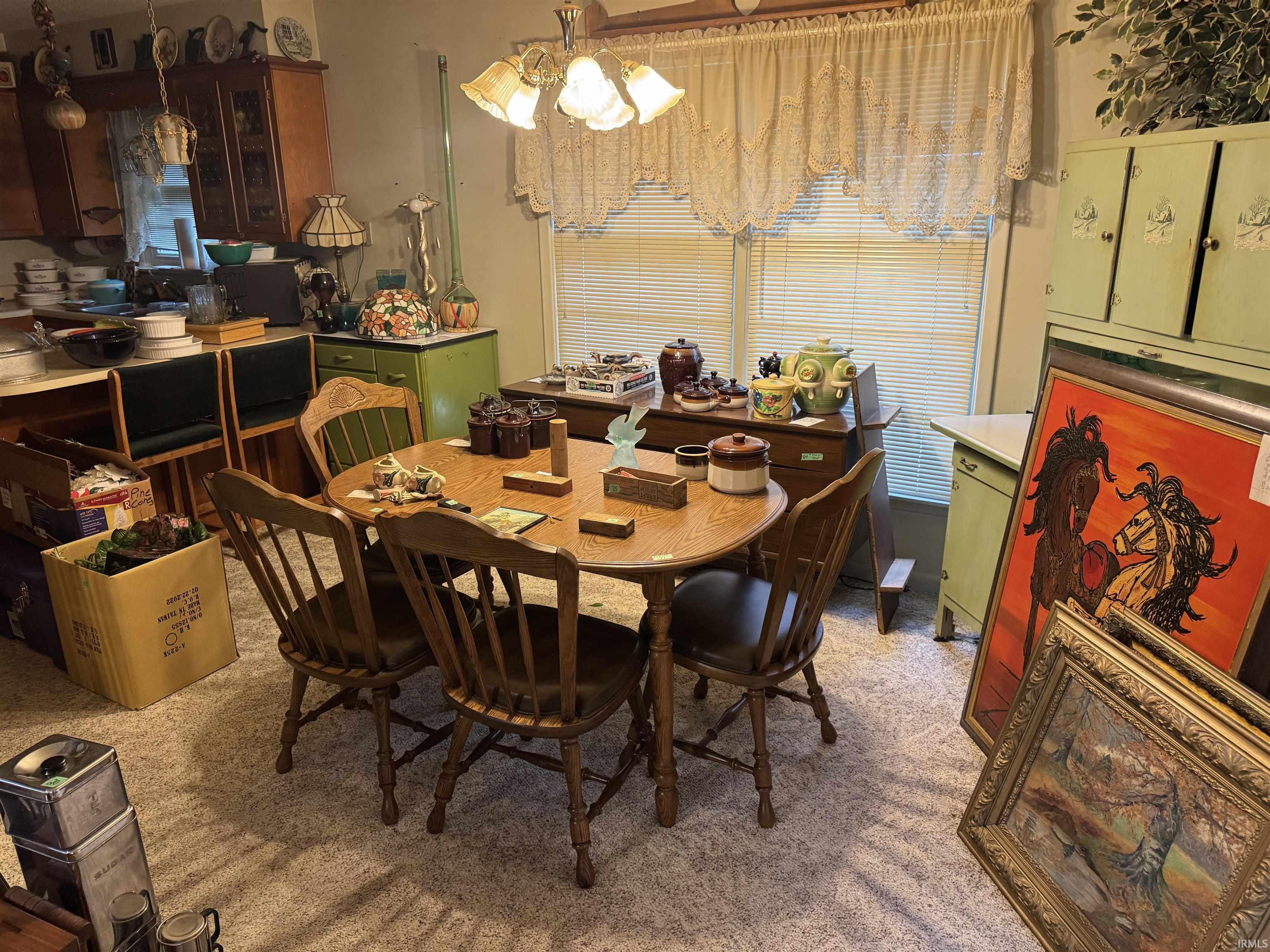 Dining area featuring a wood-finish table with seating for four, pendant lighting, textured carpet flooring, and window blinds