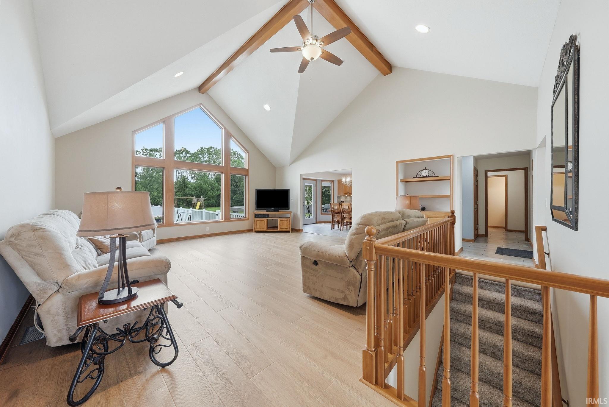 Spacious living area featuring a vaulted ceiling with exposed wood beams, a ceiling fan, and recessed lighting