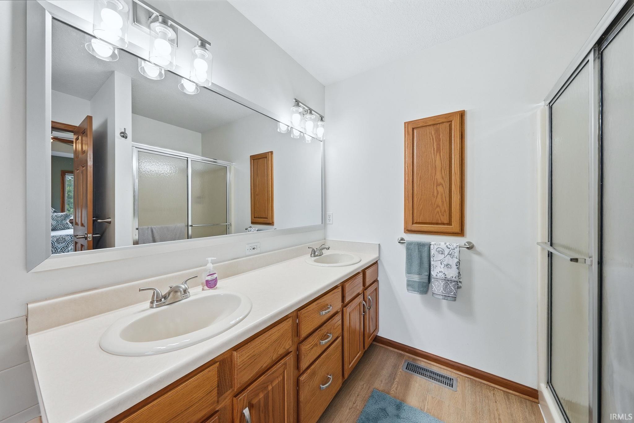 Double vanity with wood-finish cabinetry, white countertop, and dual sinks