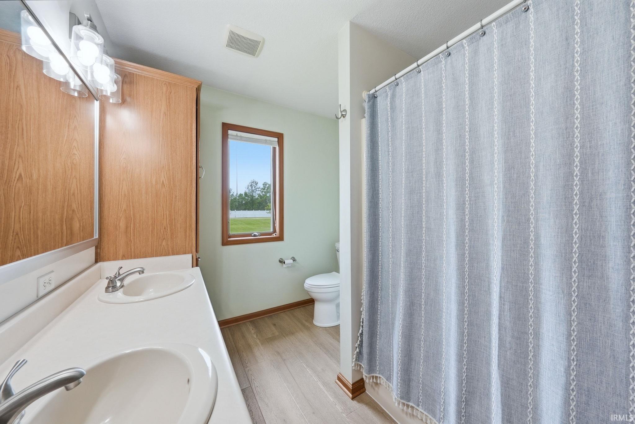 Bathroom featuring a double vanity with integrated sinks, wood-finish cabinetry, and a window with wood trim