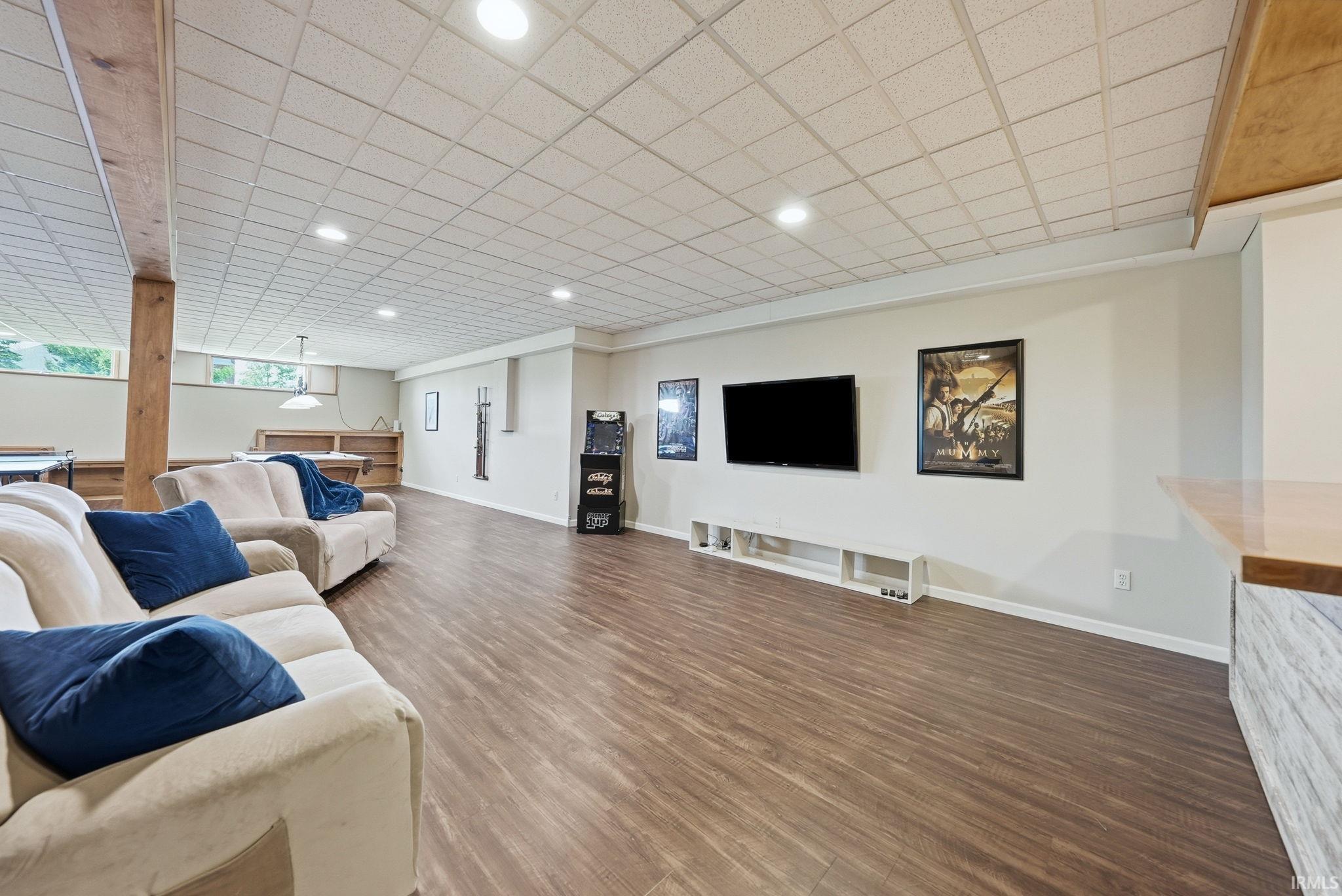 Spacious room featuring wood-finish flooring, recessed lighting, drop ceiling, and a built-in entertainment console