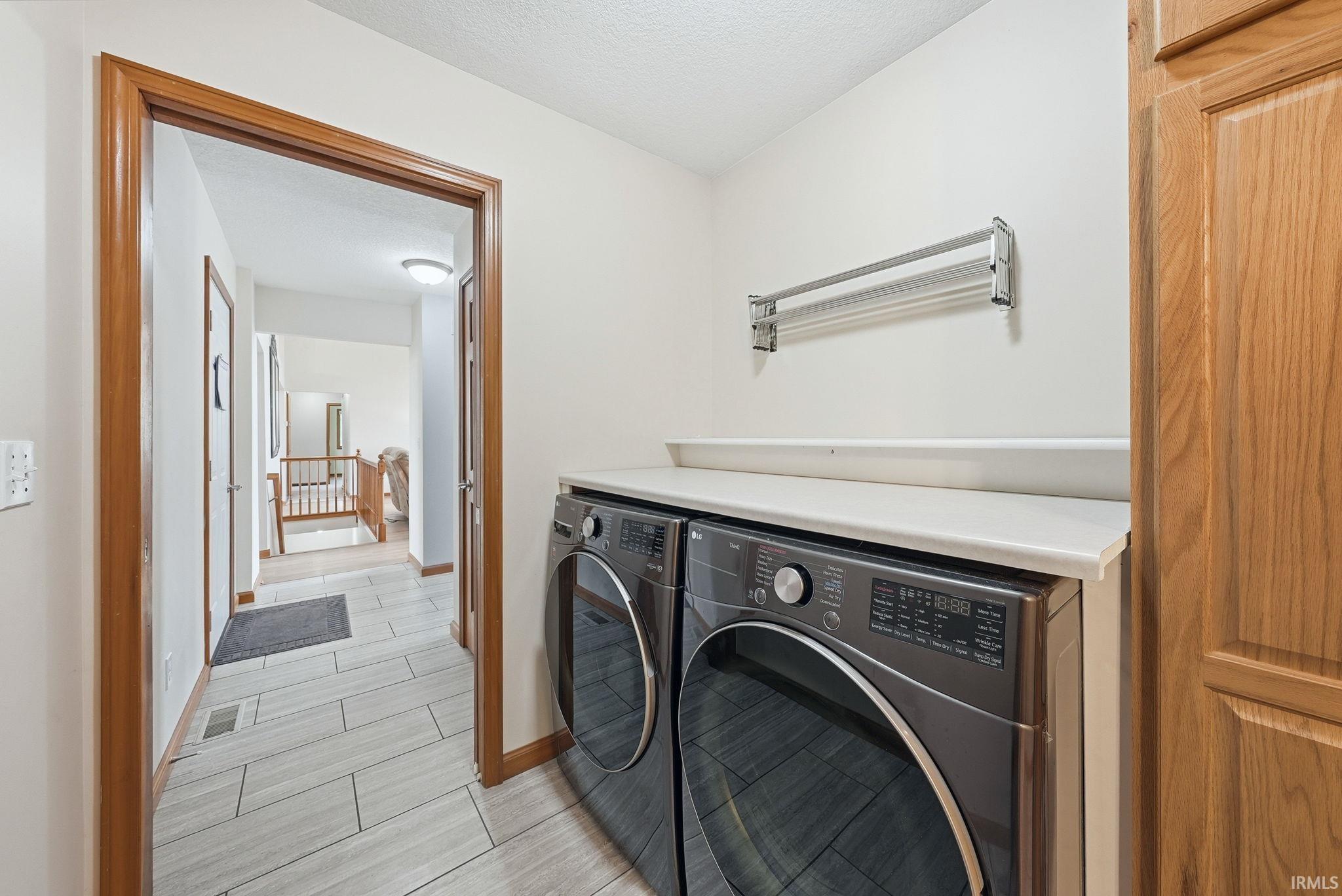 Dedicated laundry area featuring a white countertop, wall-mounted drying rack, and natural wood cabinetry