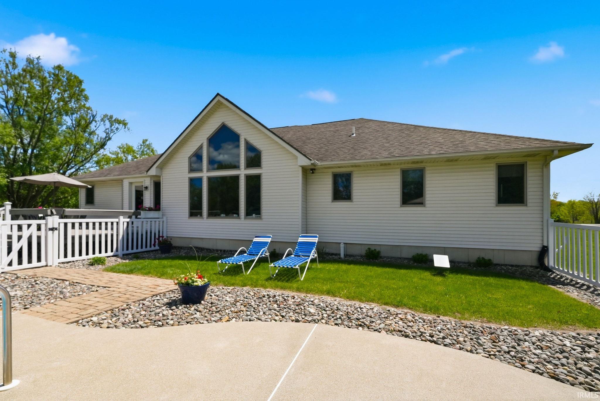 Rear exterior featuring a tall gable with a large window array, white siding, and a deck with white railing