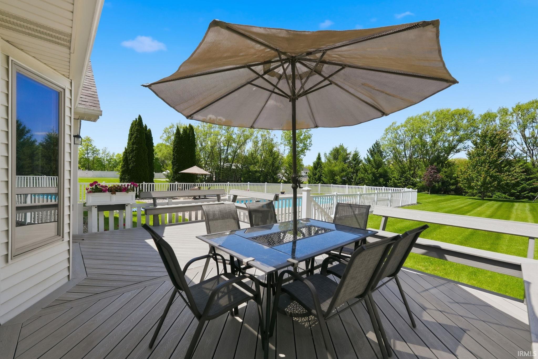 Expansive outdoor deck with a gray finish, featuring a built-in bench, white railings, and a large bay window on the home's exterior