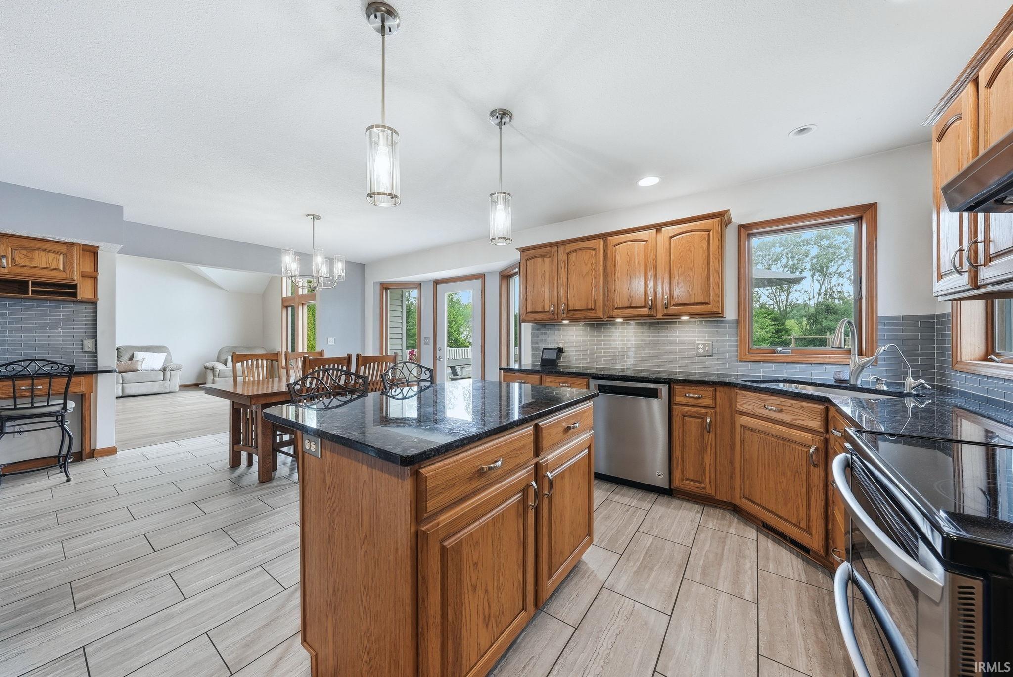Kitchen featuring wood cabinetry, dark countertops, a tiled backsplash, and stainless steel appliances