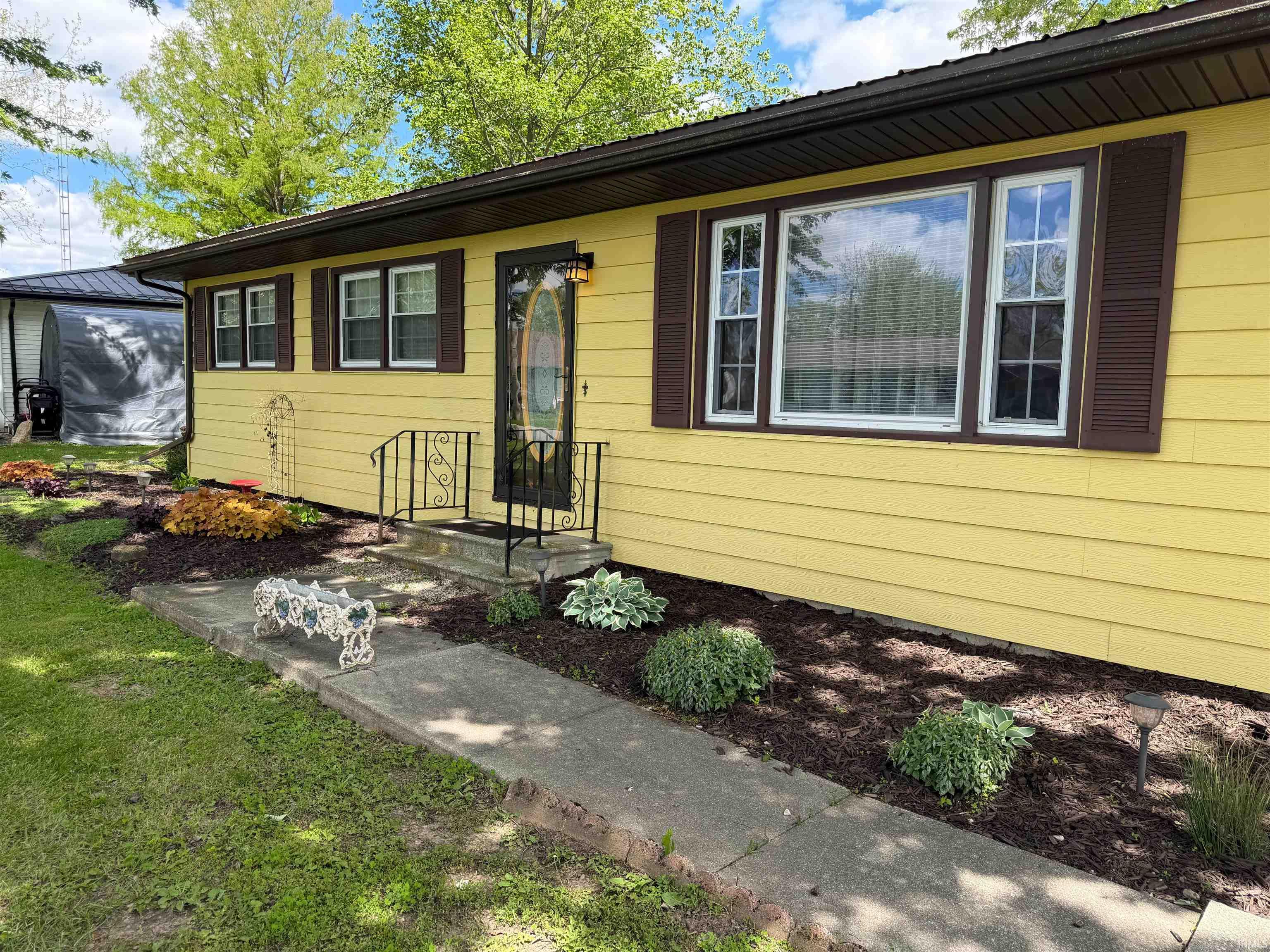 Yellow siding exterior featuring dark brown window shutters