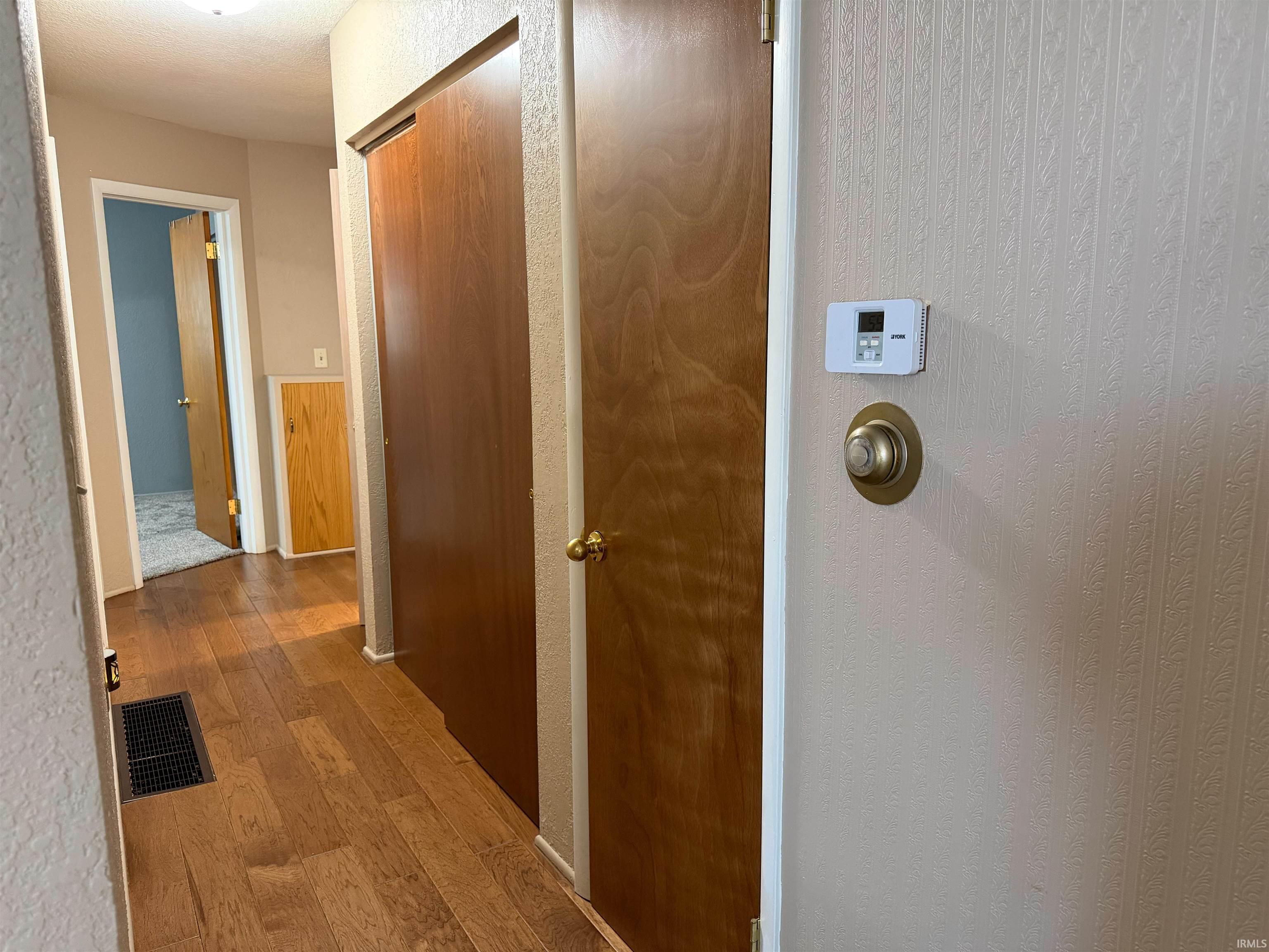Hallway featuring wood-finish flooring, light-colored walls, and solid core doors