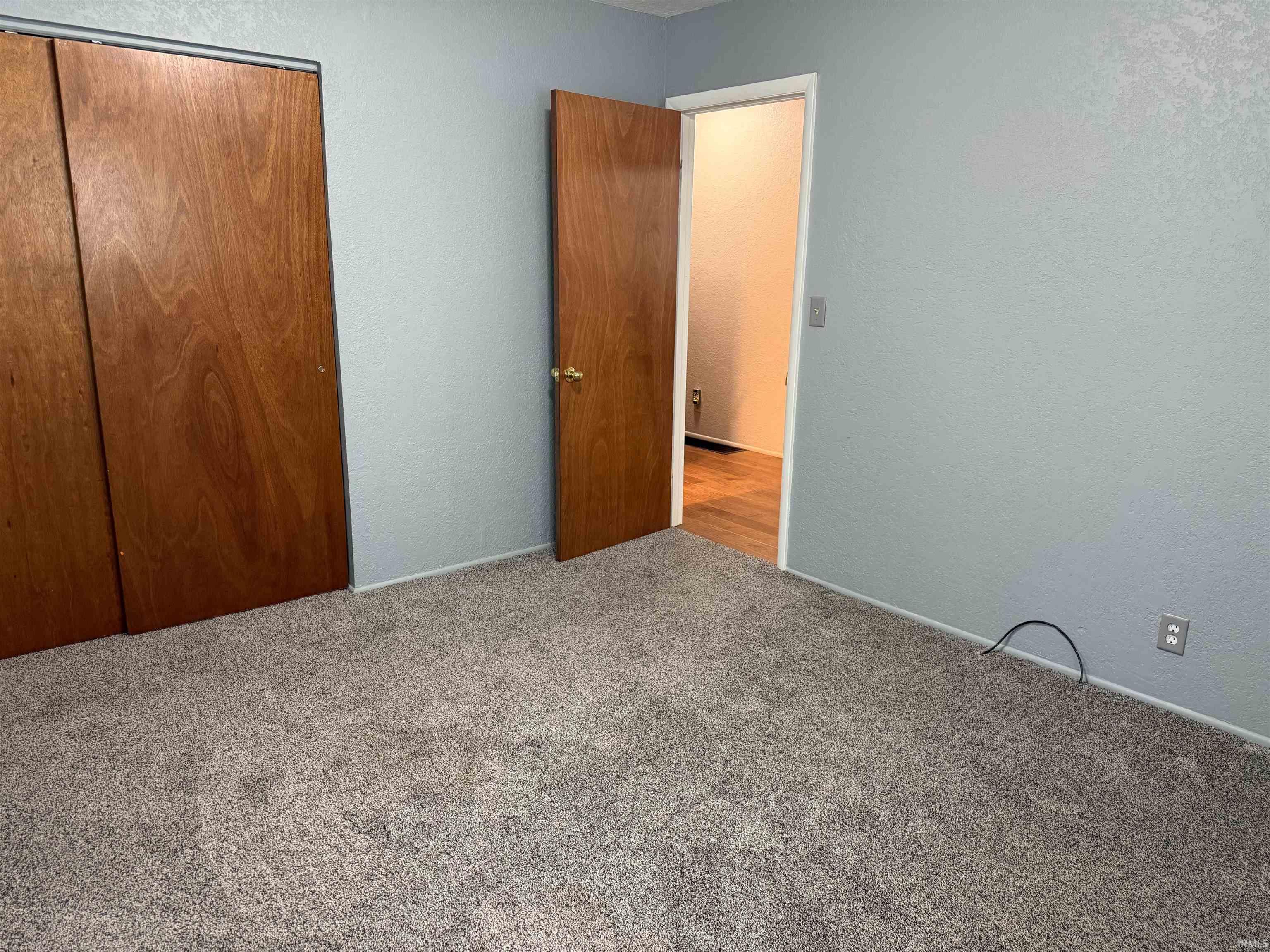 Carpeted room with a wood-finish bi-fold closet and a wood-finish door