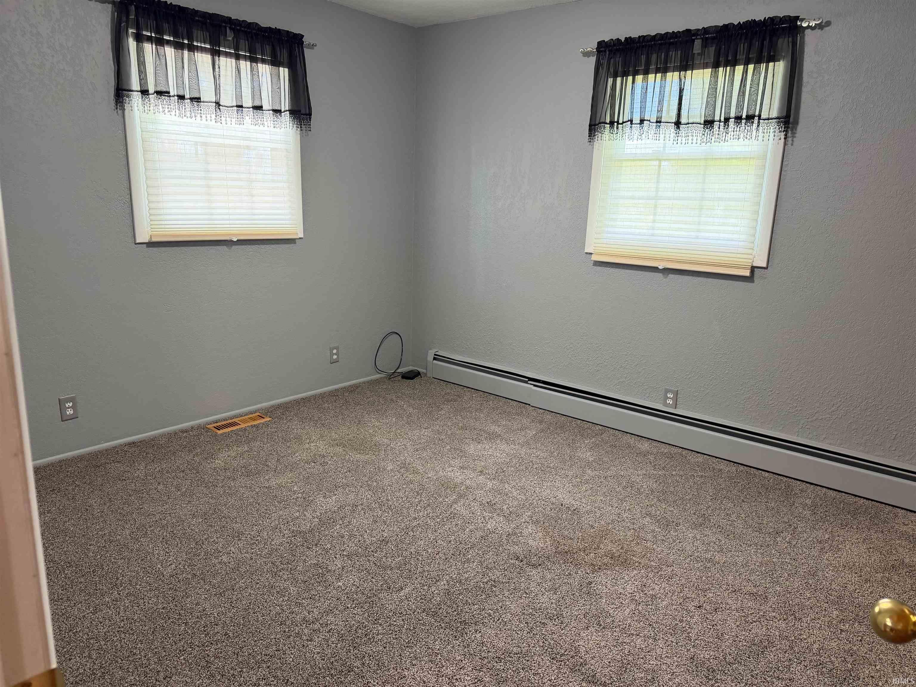 Room featuring neutral gray wall paint, two windows with blinds, and wall-to-wall carpeting