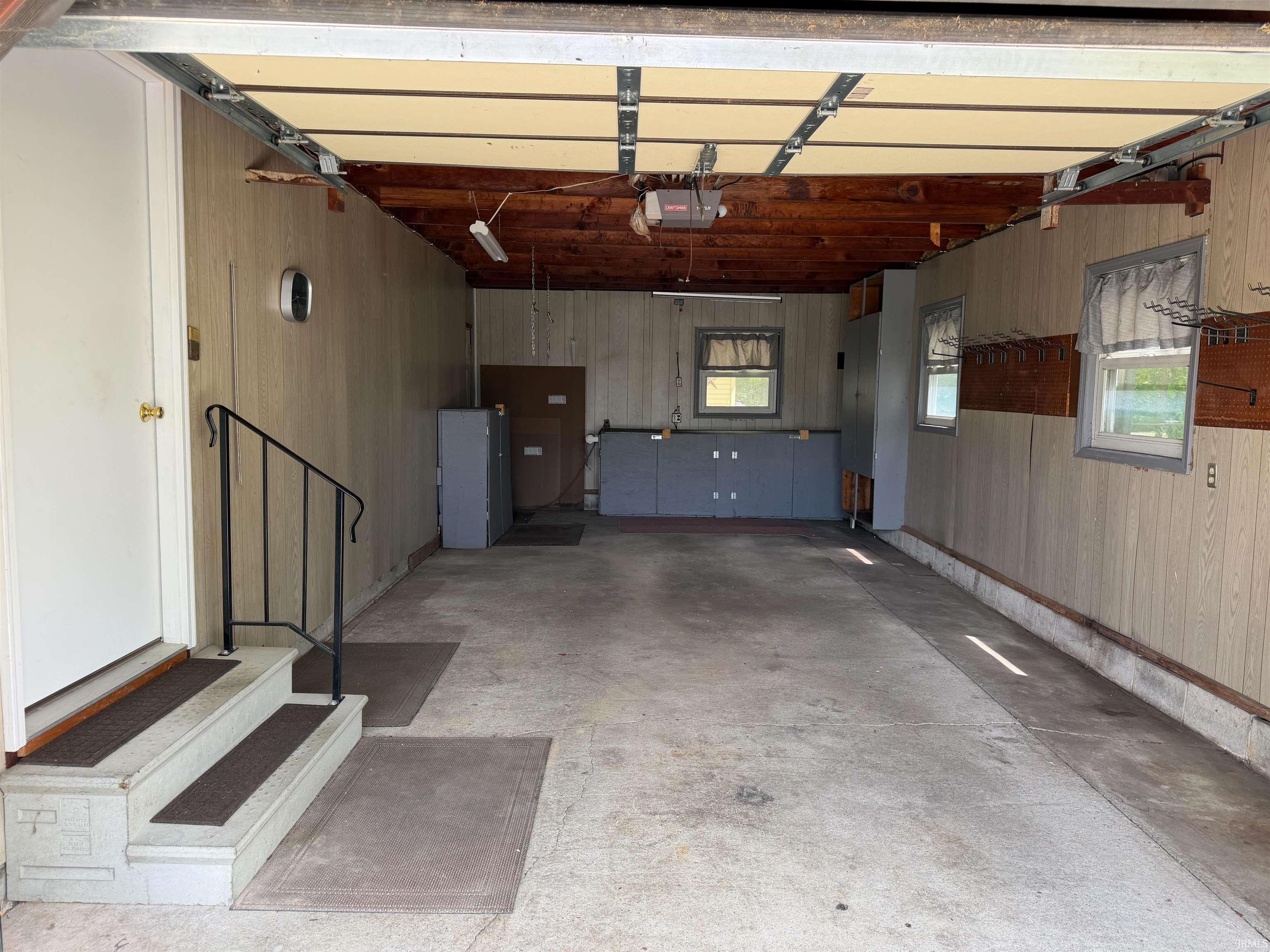 Spacious garage featuring concrete flooring, built-in cabinetry, and multiple windows for natural illumination