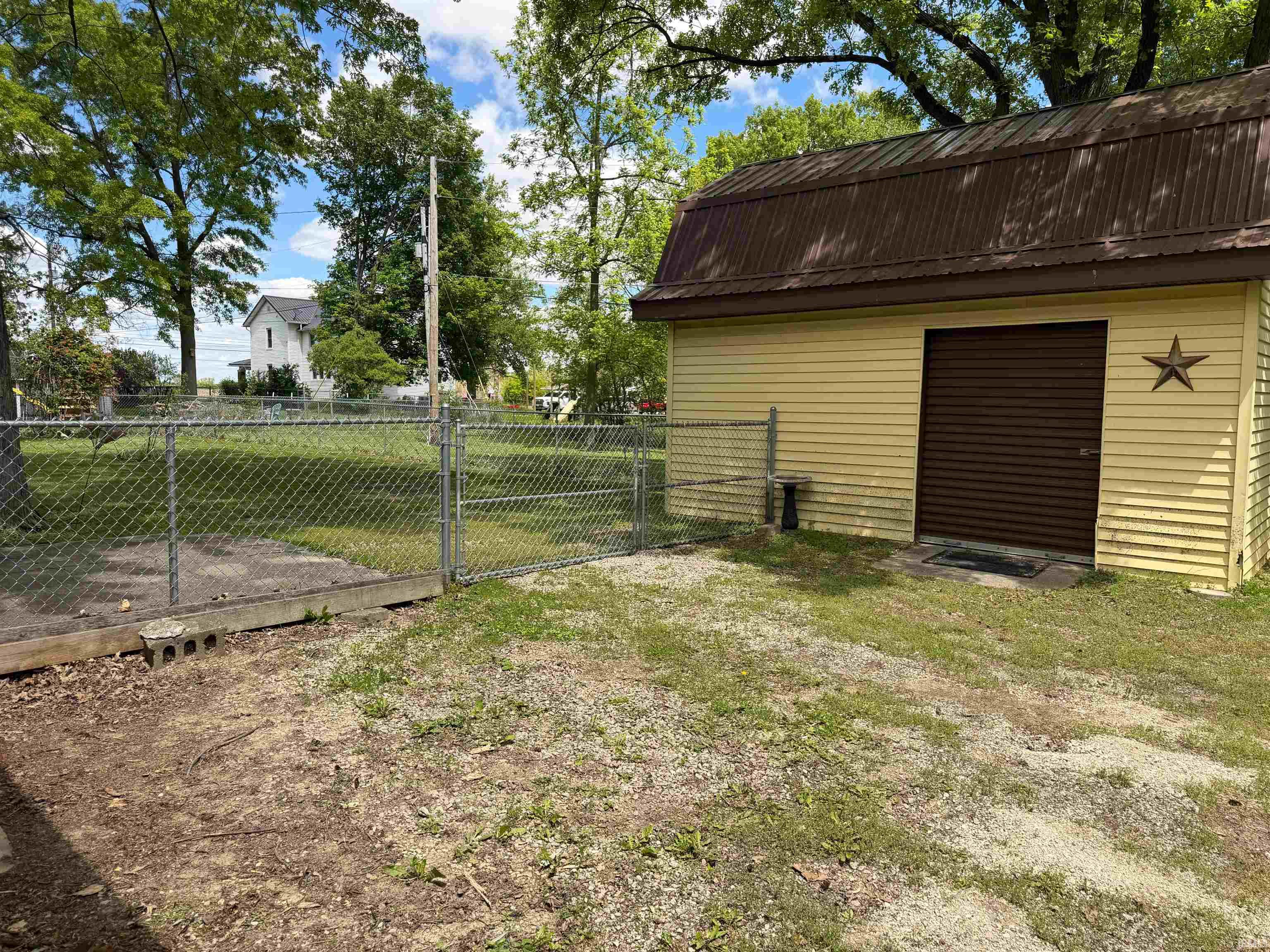 Detached accessory building featuring yellow siding, a brown metal roof, and a brown roll-up door