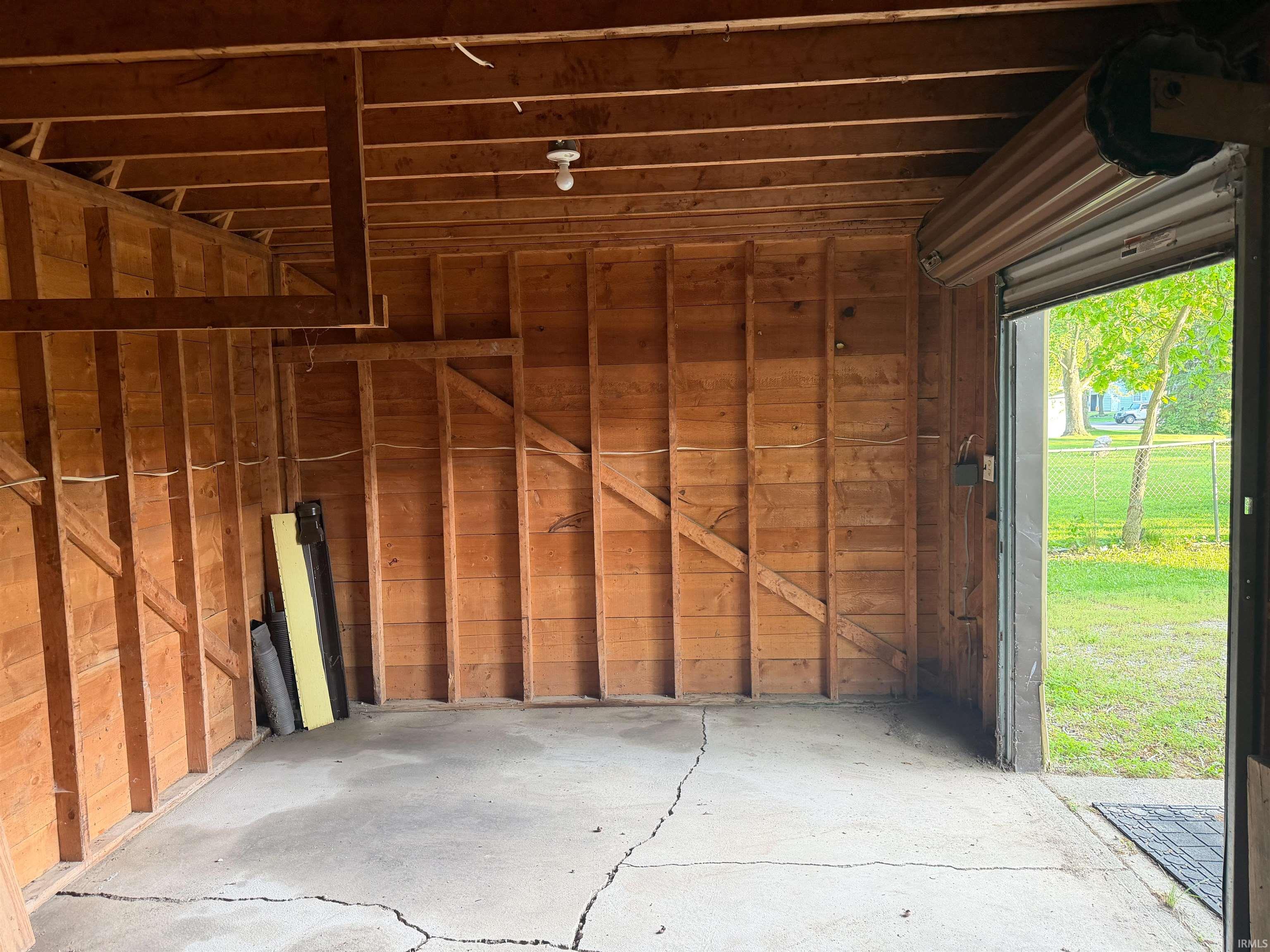 Interior garage space featuring exposed wood framing and a concrete floor