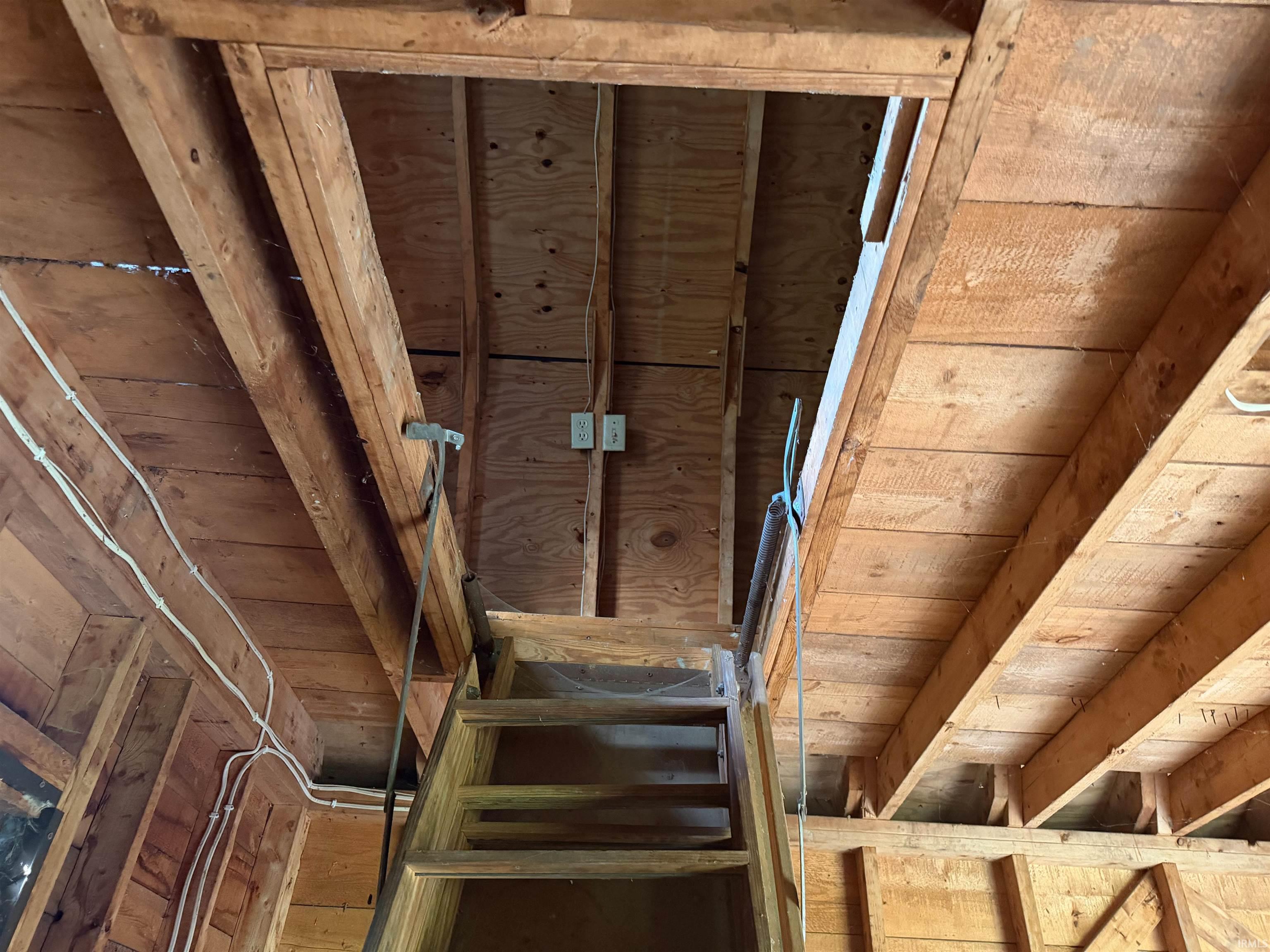 Wooden attic access ladder positioned beneath exposed wood framing