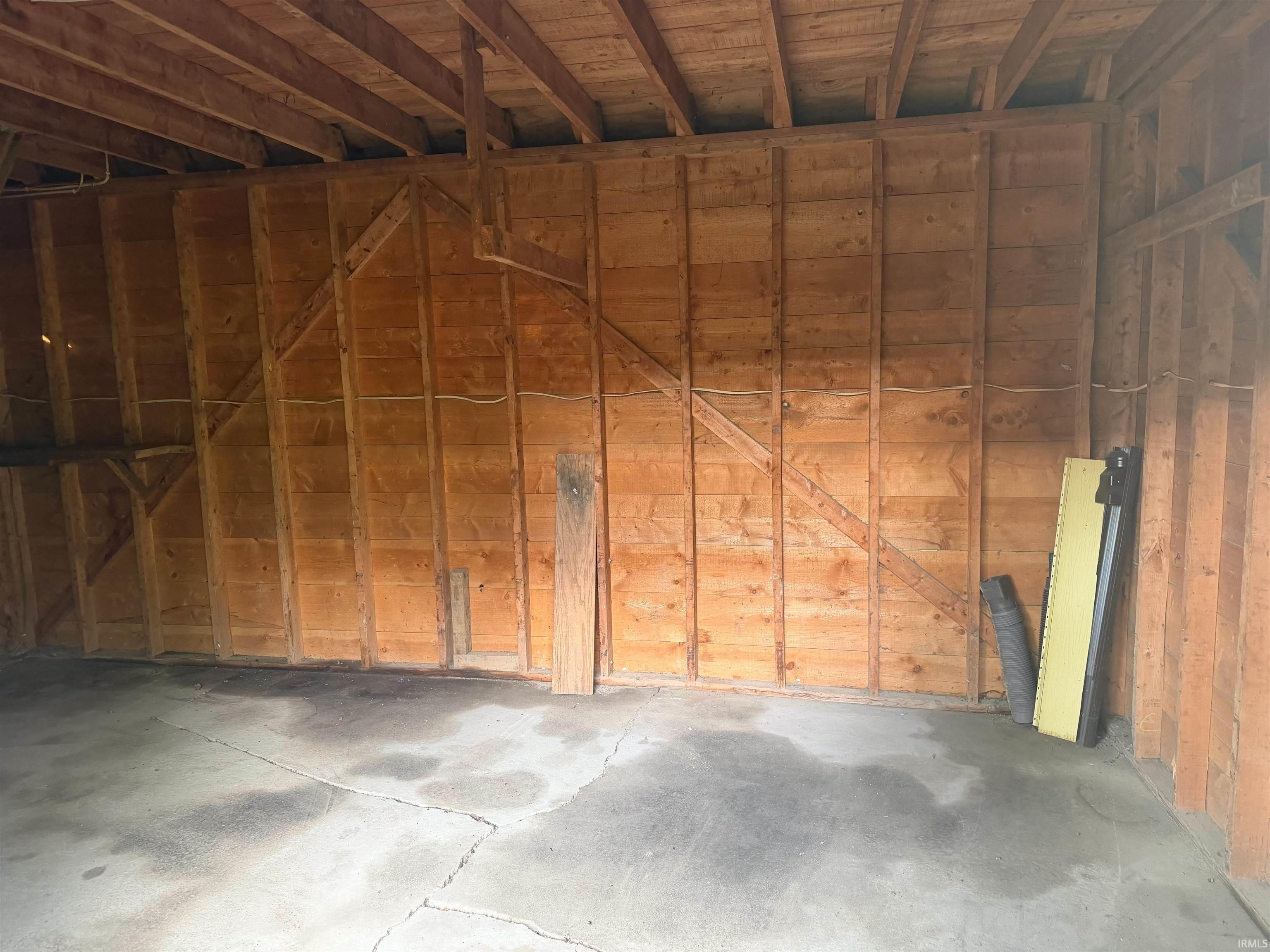 Garage interior featuring exposed wood framing and a concrete floor