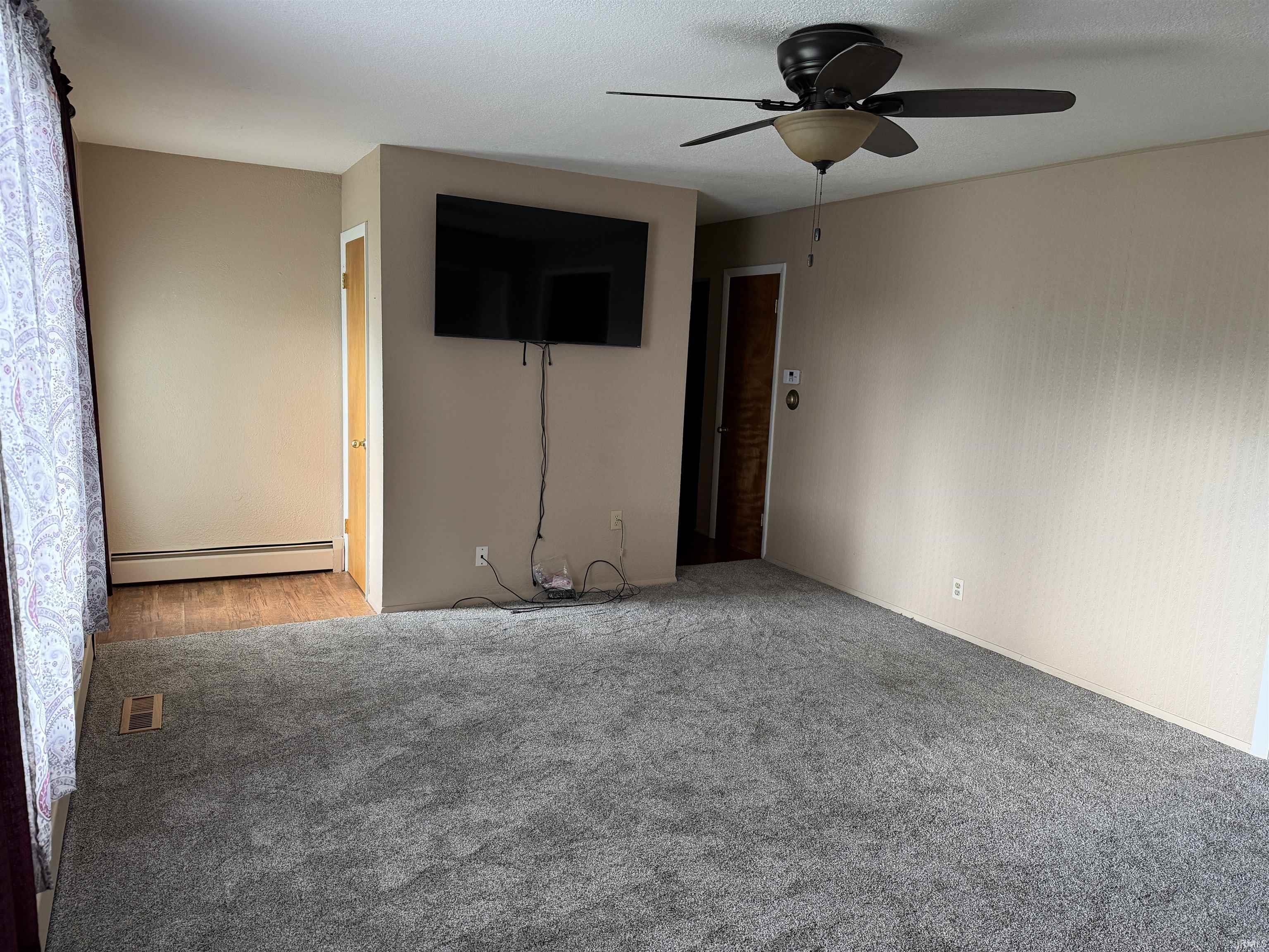 Spacious room with neutral wall tones and a ceiling fan light fixture