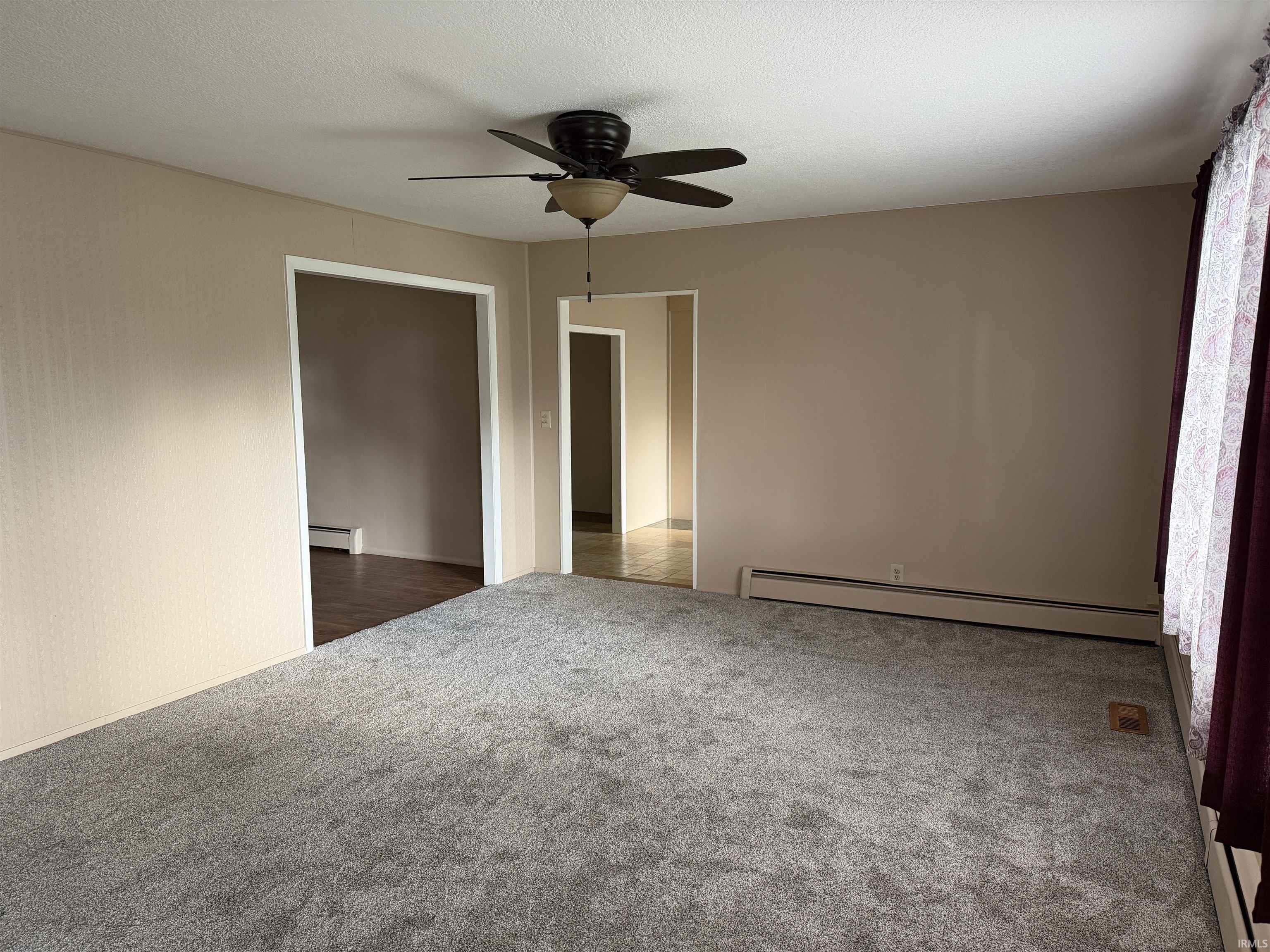 Open-concept room featuring neutral paint, grey carpeting, a ceiling fan with integrated lighting, and multiple doorways