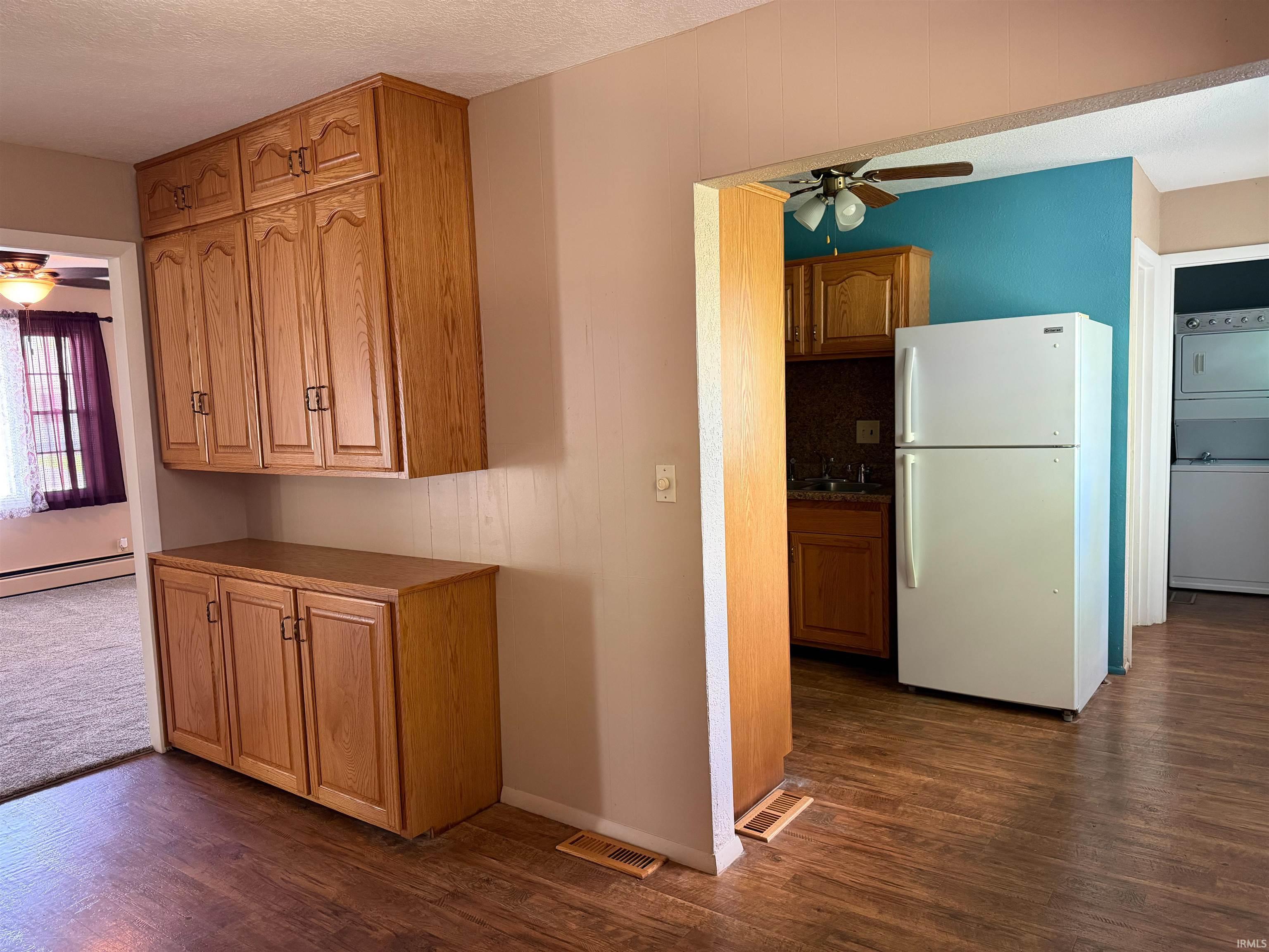 Wood-finish flooring throughout, featuring a built-in wood cabinet system, and a separate kitchen area with a ceiling fan