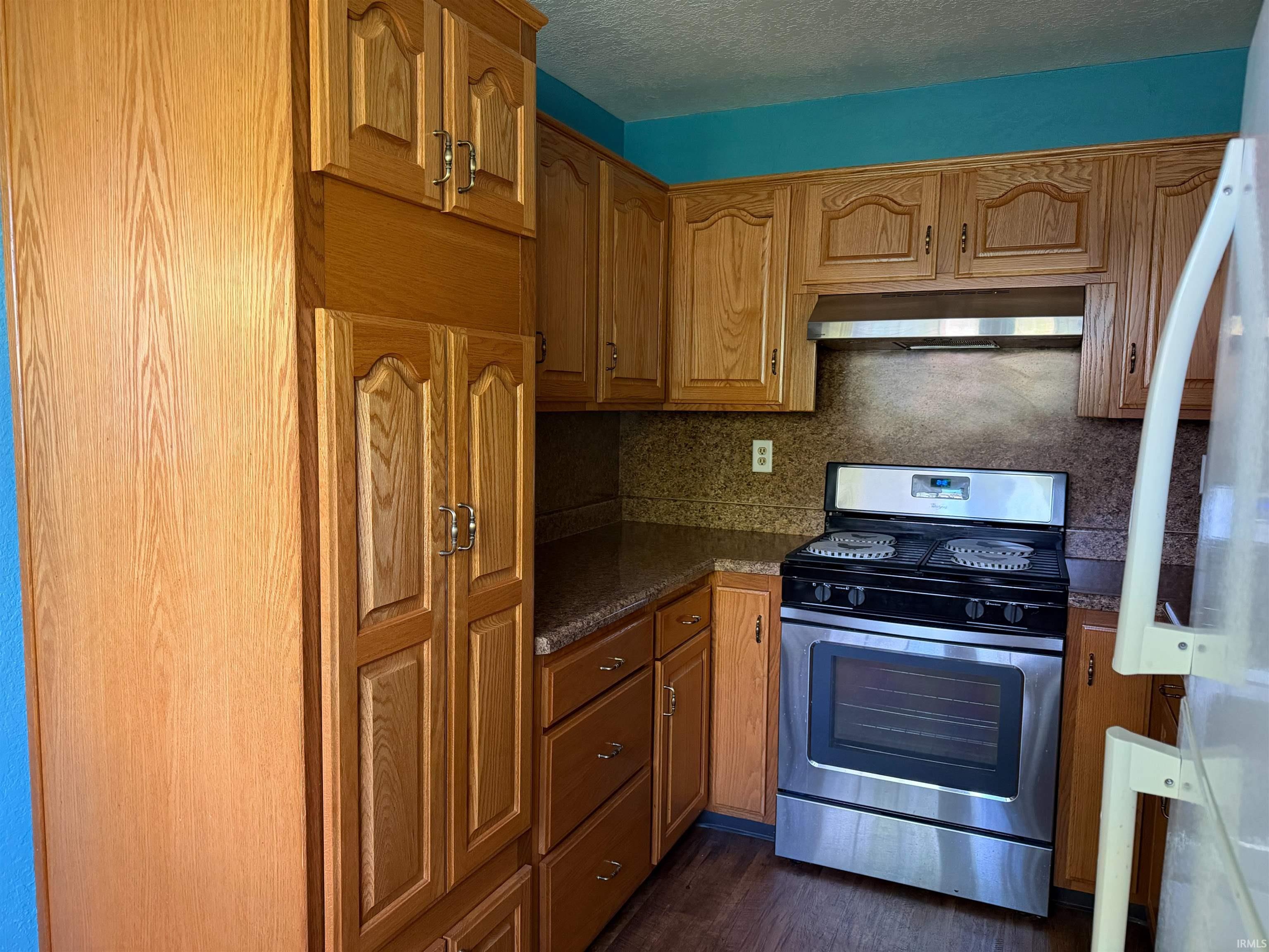 Kitchen featuring wood-finish cabinetry, stainless steel range with overhead ventilation, and a built-in pantry