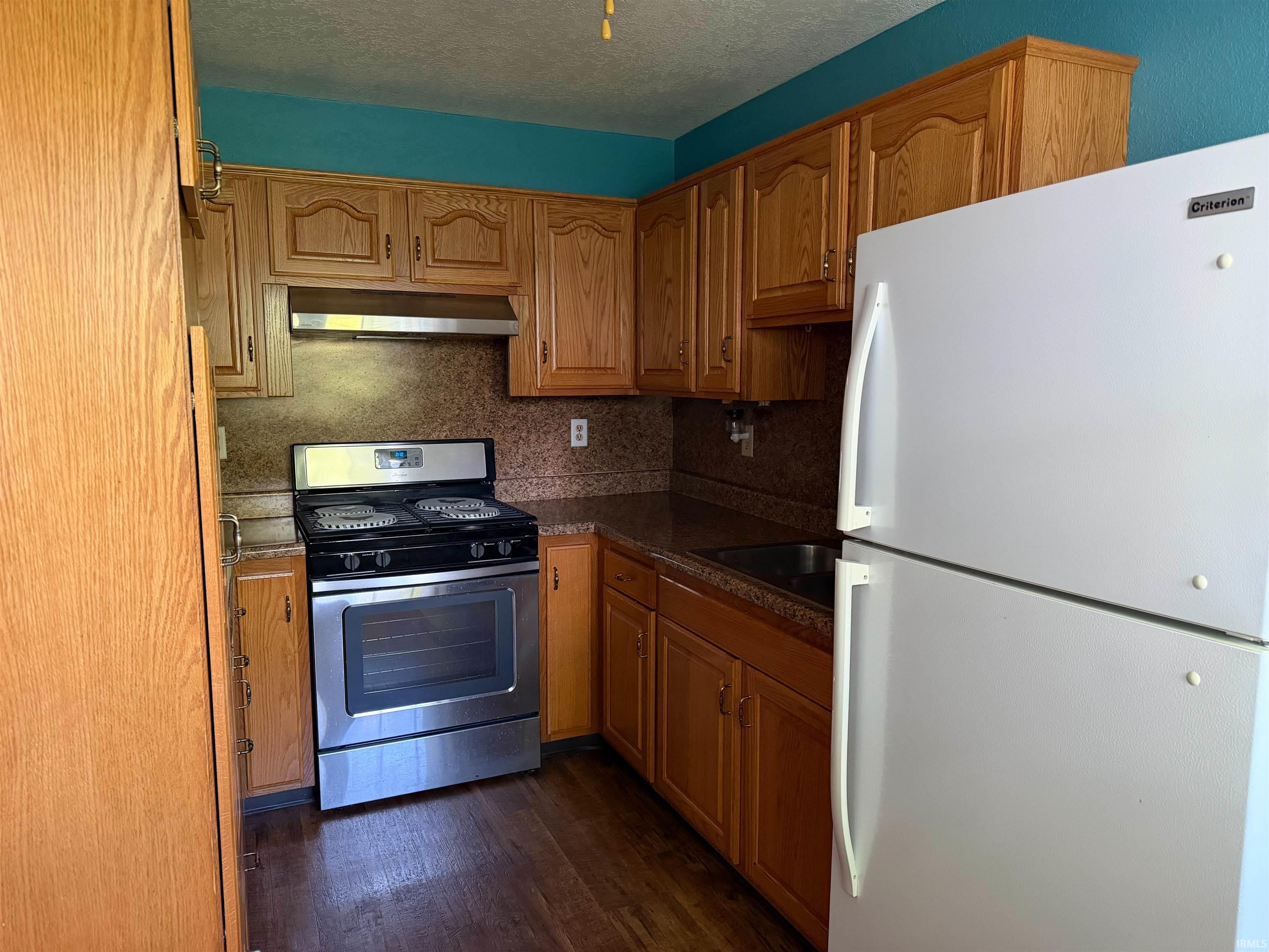 Kitchen featuring wood-finish cabinetry, dark countertops, and a stainless steel oven/range