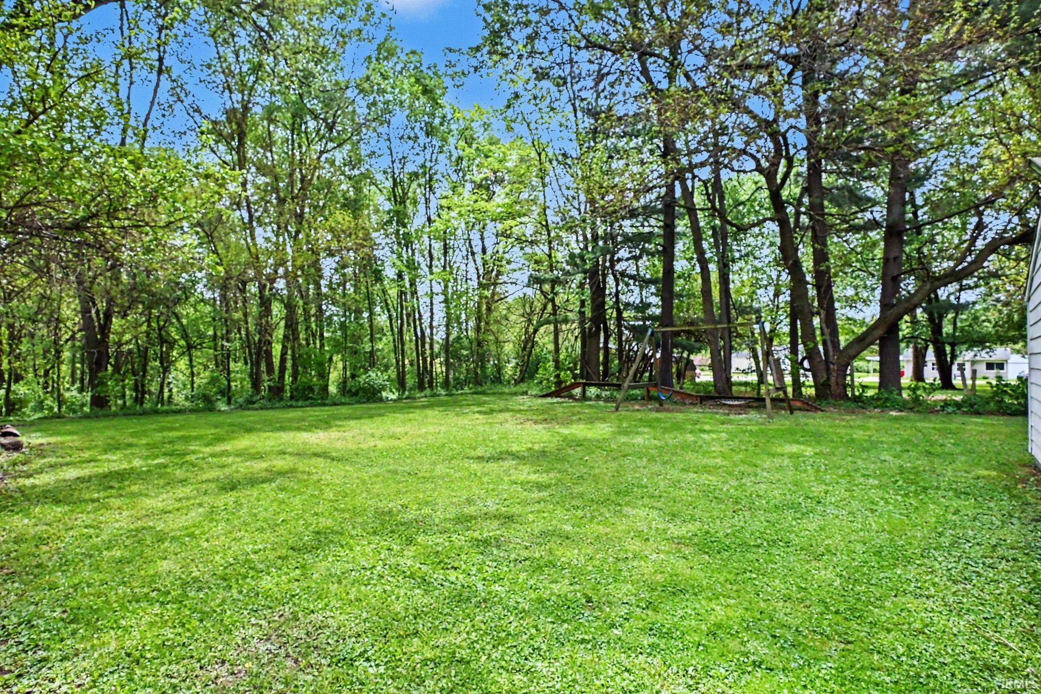 Expansive green lawn surrounded by mature trees, offering a private outdoor setting