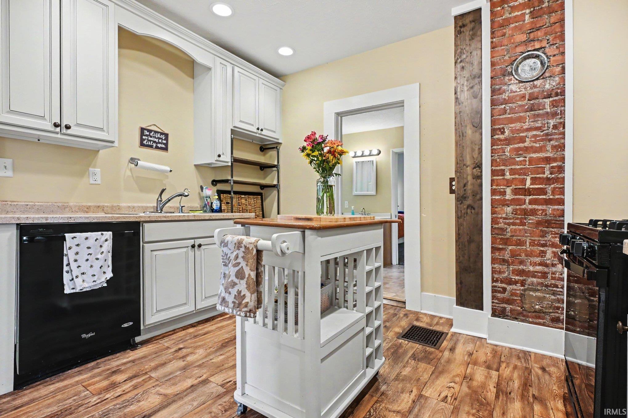 Kitchen featuring wood-finish flooring, white cabinetry, and a mobile island with a butcher block top