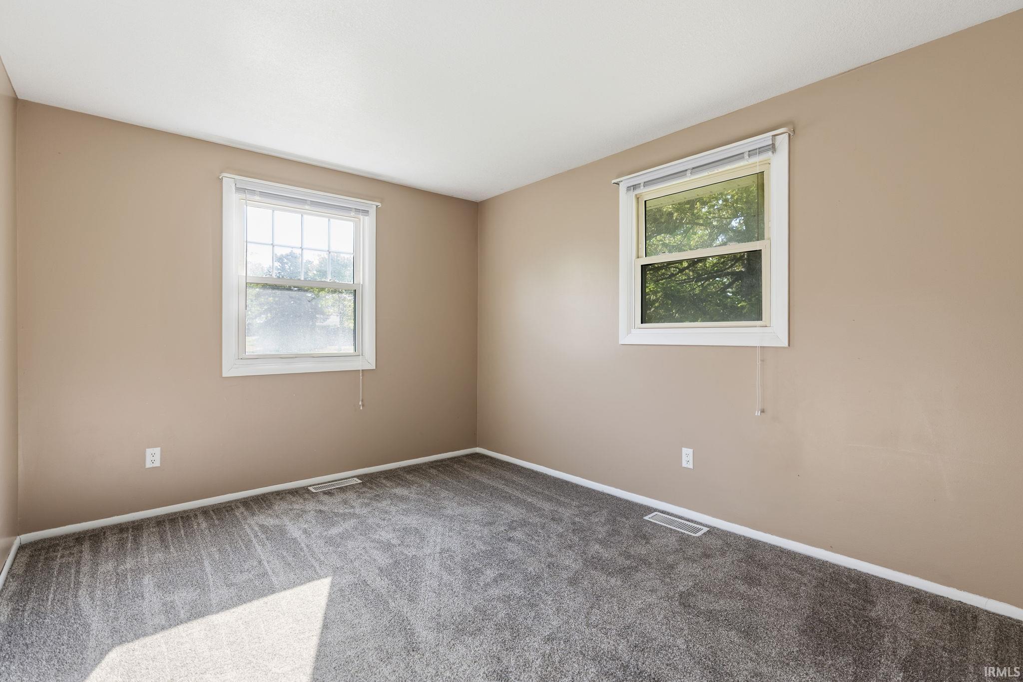 Neutral tone walls with white trim, two double-hung windows, and gray patterned carpet