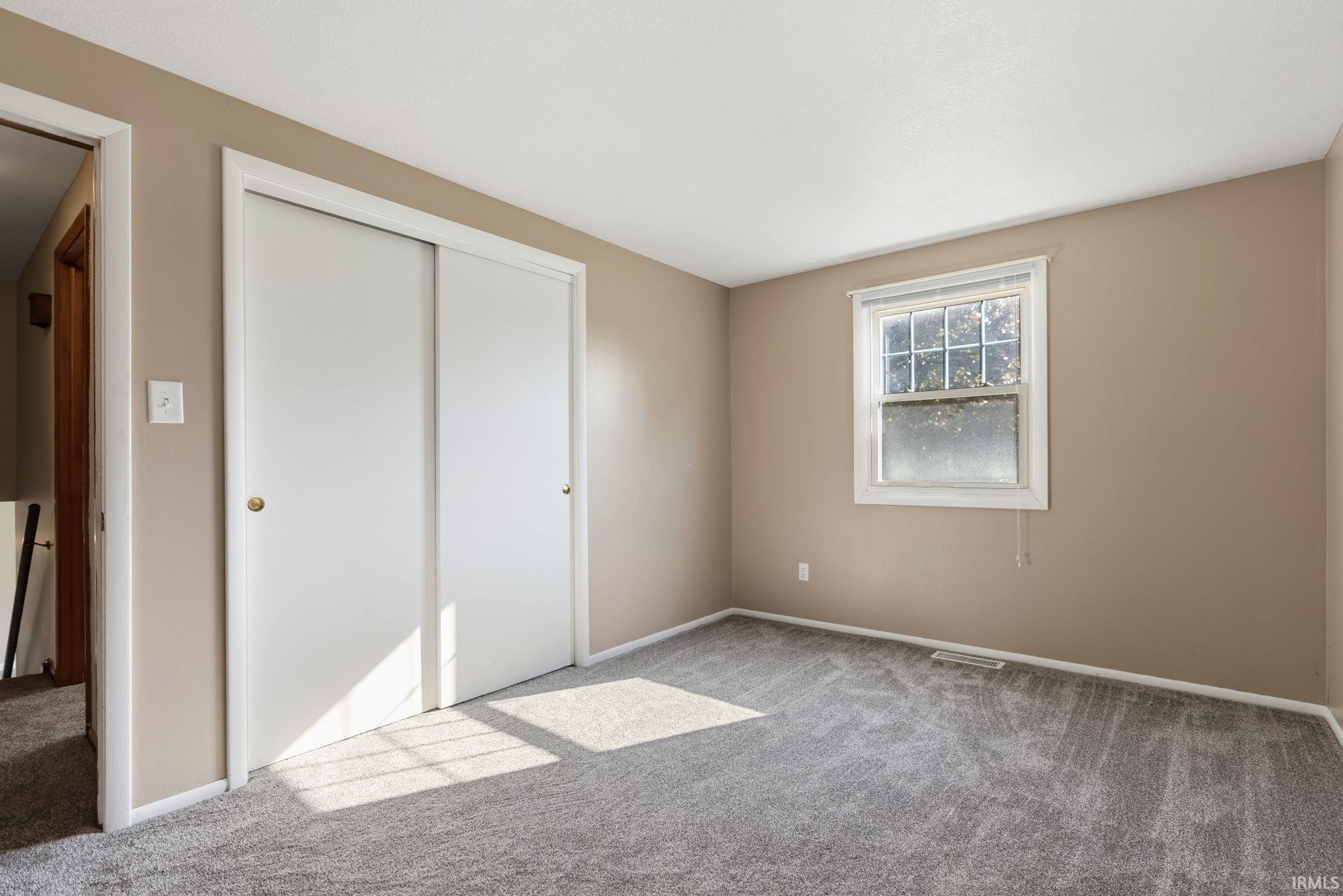 Bedroom with neutral-toned walls and light gray carpeting