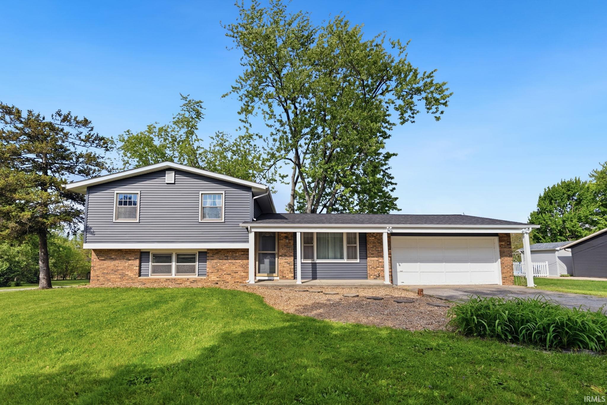 Split-level residence featuring gray siding and a brick facade