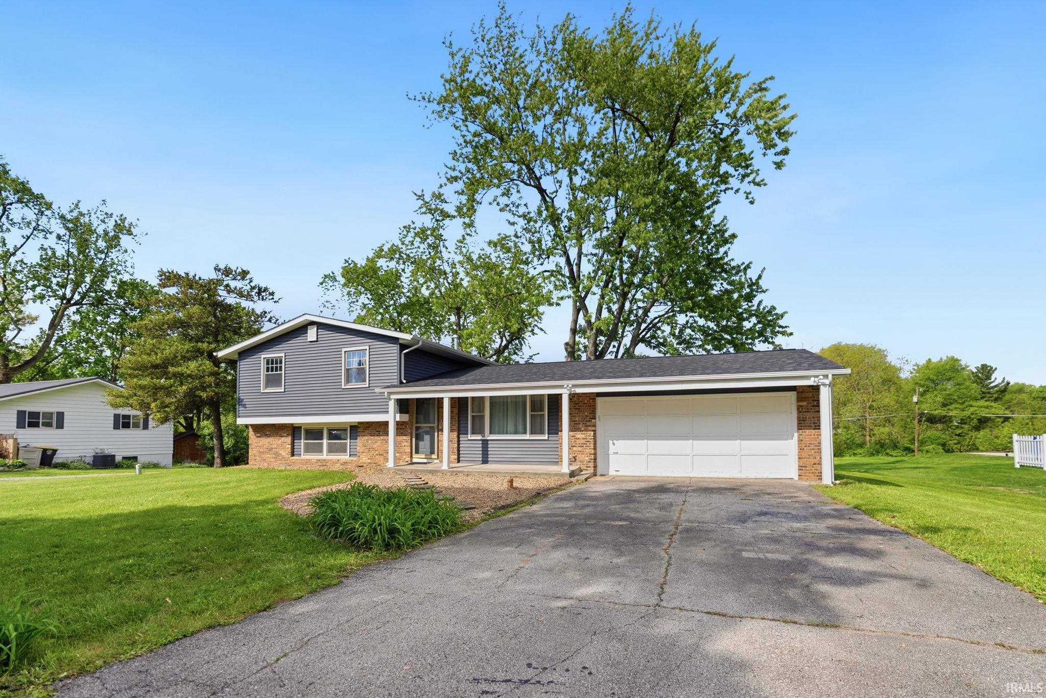 Split-level residence featuring gray siding, a brick facade, and a two-car garage