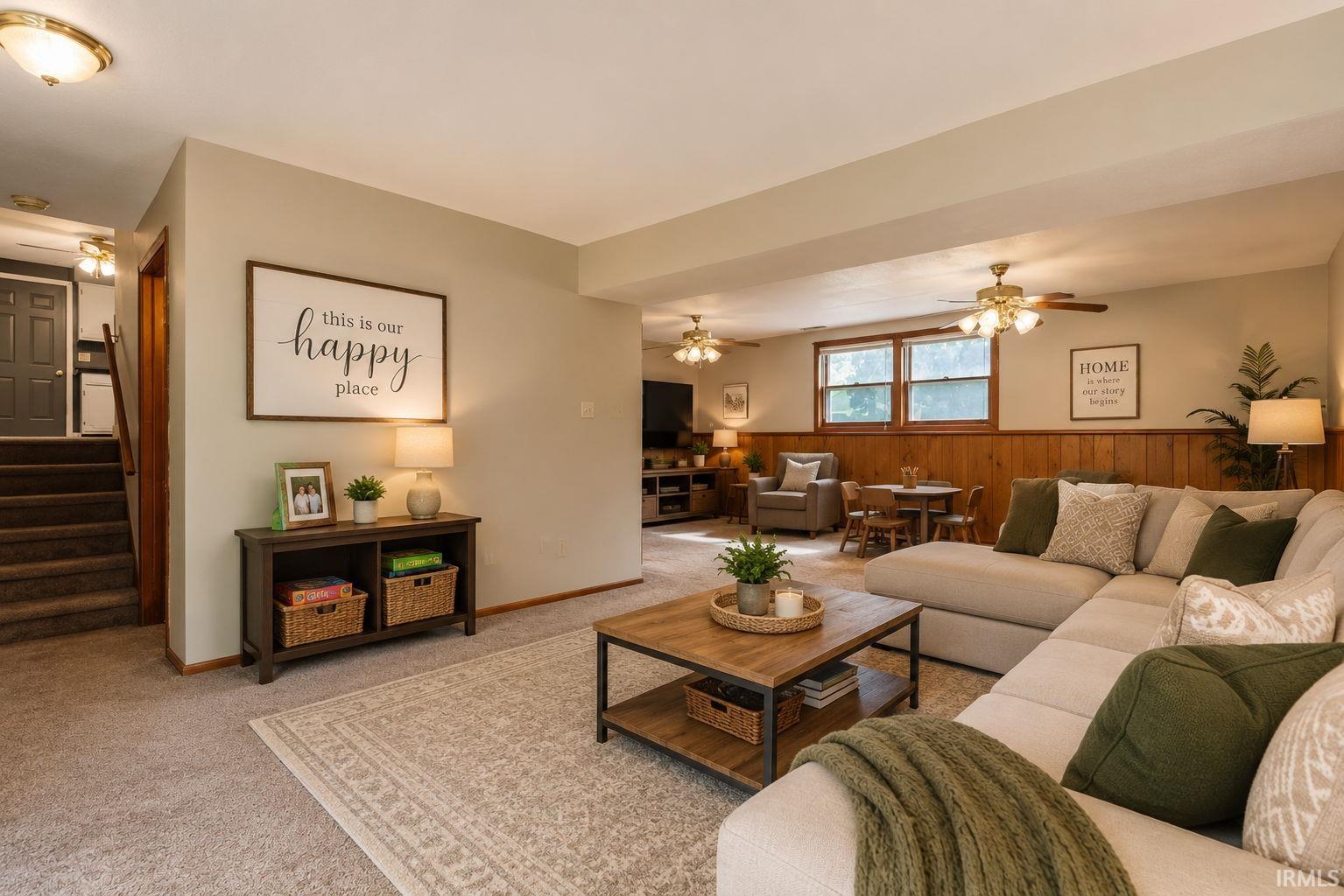 Spacious living area featuring neutral carpeting, light-toned walls, and wood-paneled accents