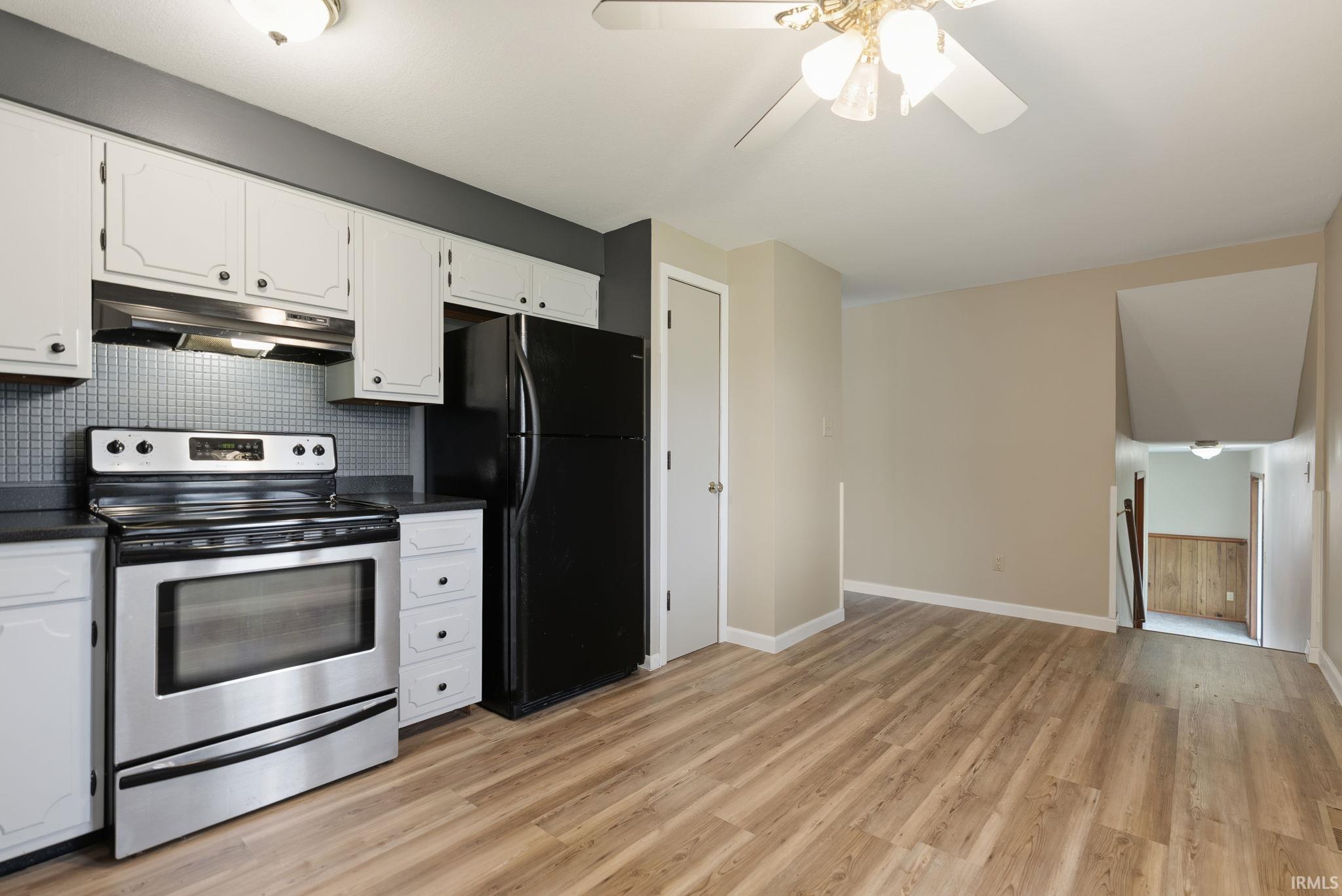 Kitchen featuring white cabinetry, dark countertops, a stainless steel range, and a full-size black refrigerator