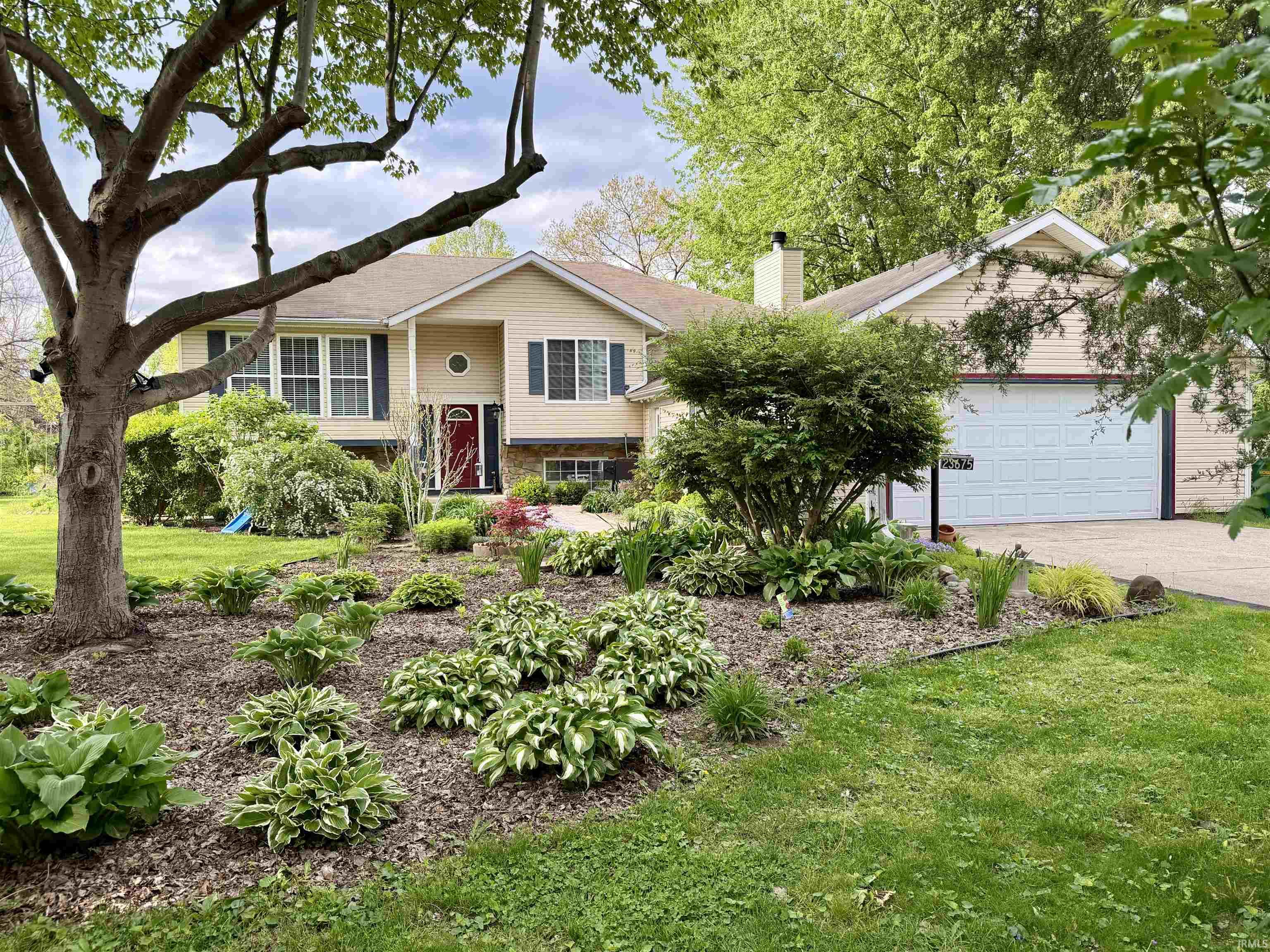 Siding exterior with stone accents, a red entry door, and dark shutters