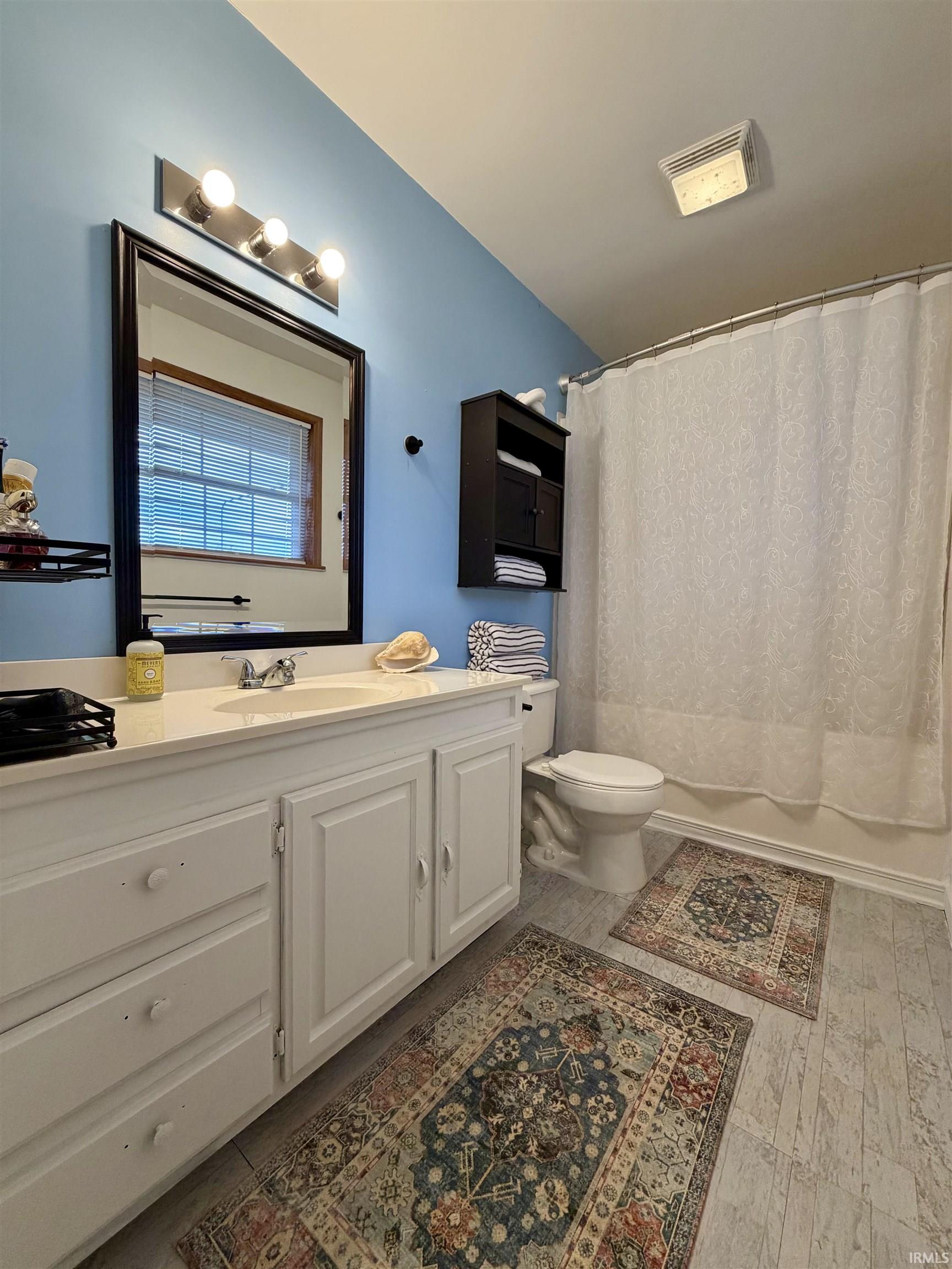 Full bathroom featuring a white vanity with integrated sink, a dark framed mirror, and a wall-mounted medicine cabinet