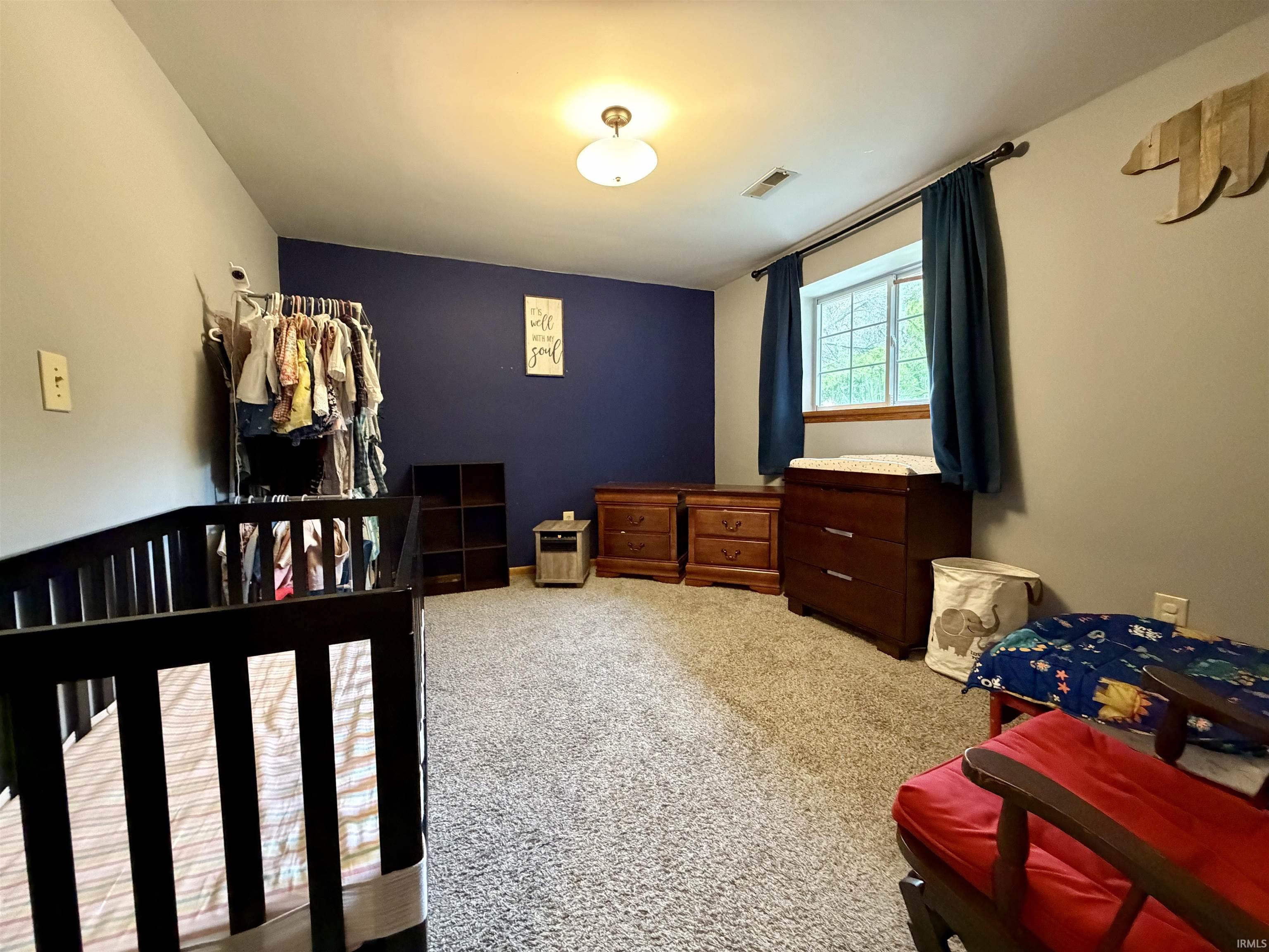 Spacious room featuring plush carpeting, a large window, and an overhead light fixture
