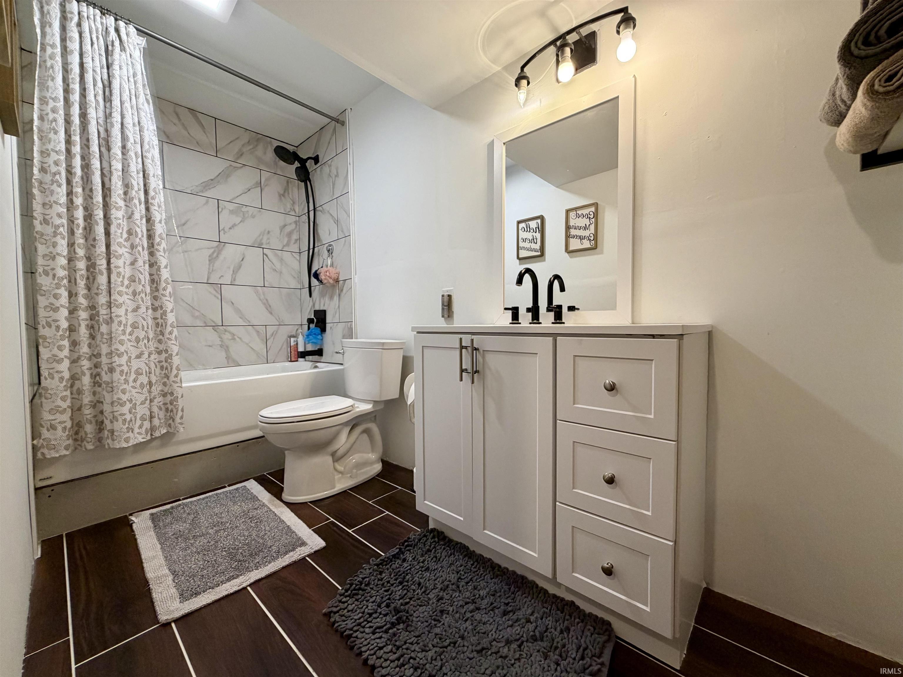 Bathroom featuring a white vanity with panel cabinetry and drawer storage, black hardware, and a framed mirror