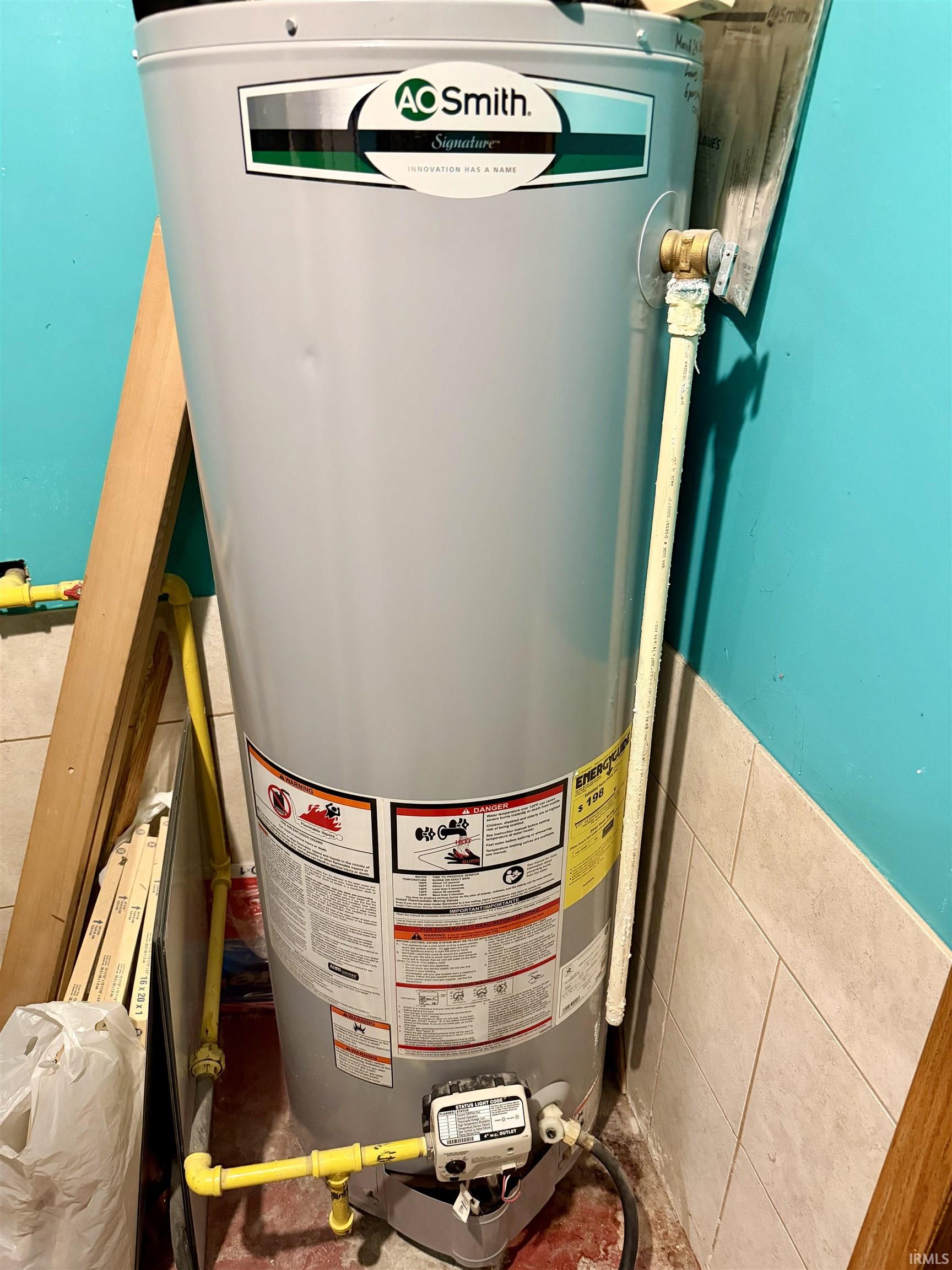 AC Smith water heater installation featuring exposed yellow gas lines and a beige tile wainscot
