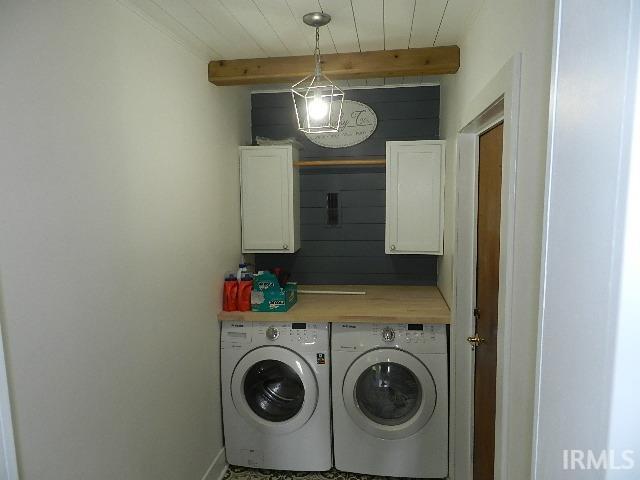 Dedicated utility space featuring a wood-finish countertop, two white upper cabinets, and a shiplap accent wall
