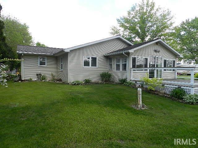 Beige vinyl siding exterior with an expansive wooden deck featuring a white lattice skirt