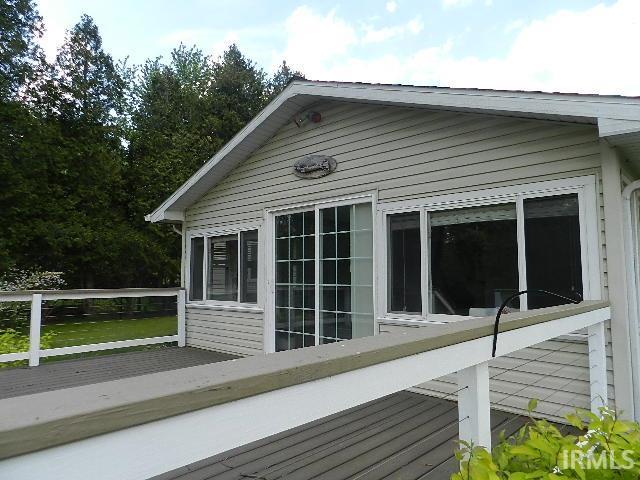 Exterior featuring light-colored siding, multiple windows, a sliding glass door, and a deck with a white railing