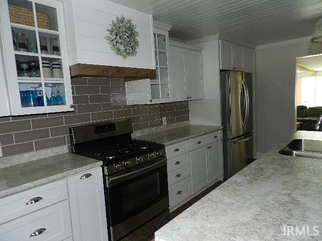 Kitchen featuring white cabinetry, gray subway tile backsplash, stainless steel appliances, light-toned countertops, and a beadboard ceiling