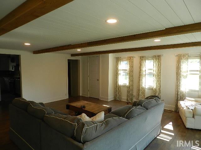 Living area featuring wood-finish flooring, exposed wood beams, recessed lighting, white shiplap ceiling, and multiple windows