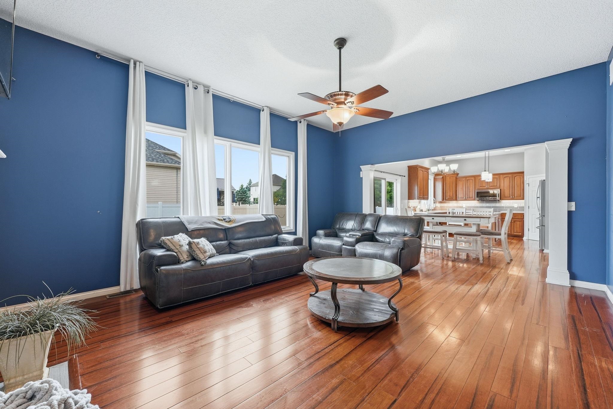 Spacious living area featuring high ceilings, wood-finish flooring, and multiple tall windows
