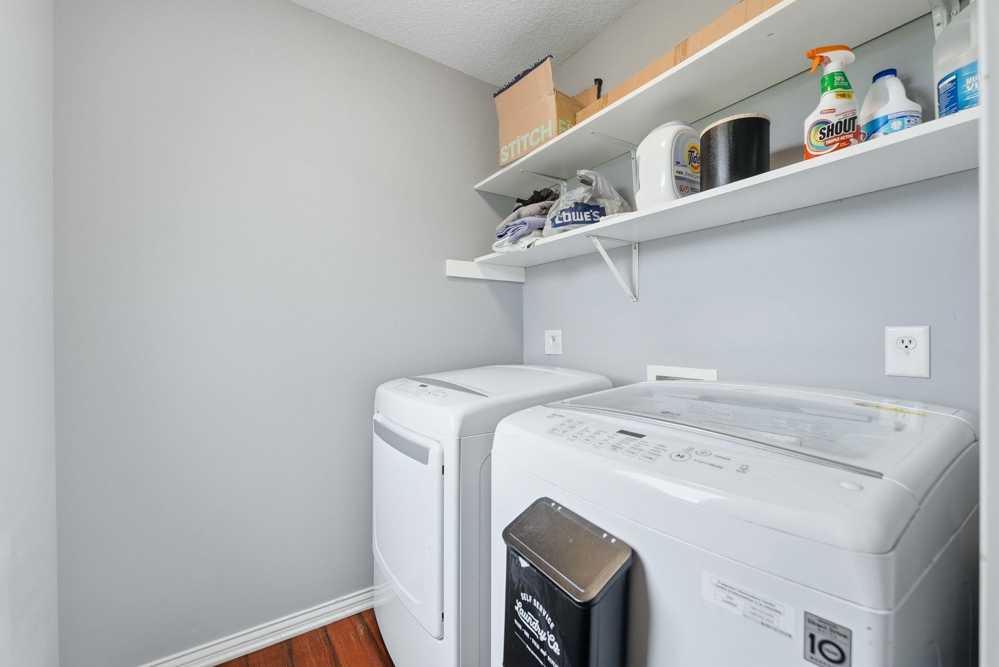 Dedicated laundry area featuring wood-finish flooring, light gray wall paint, and white baseboards