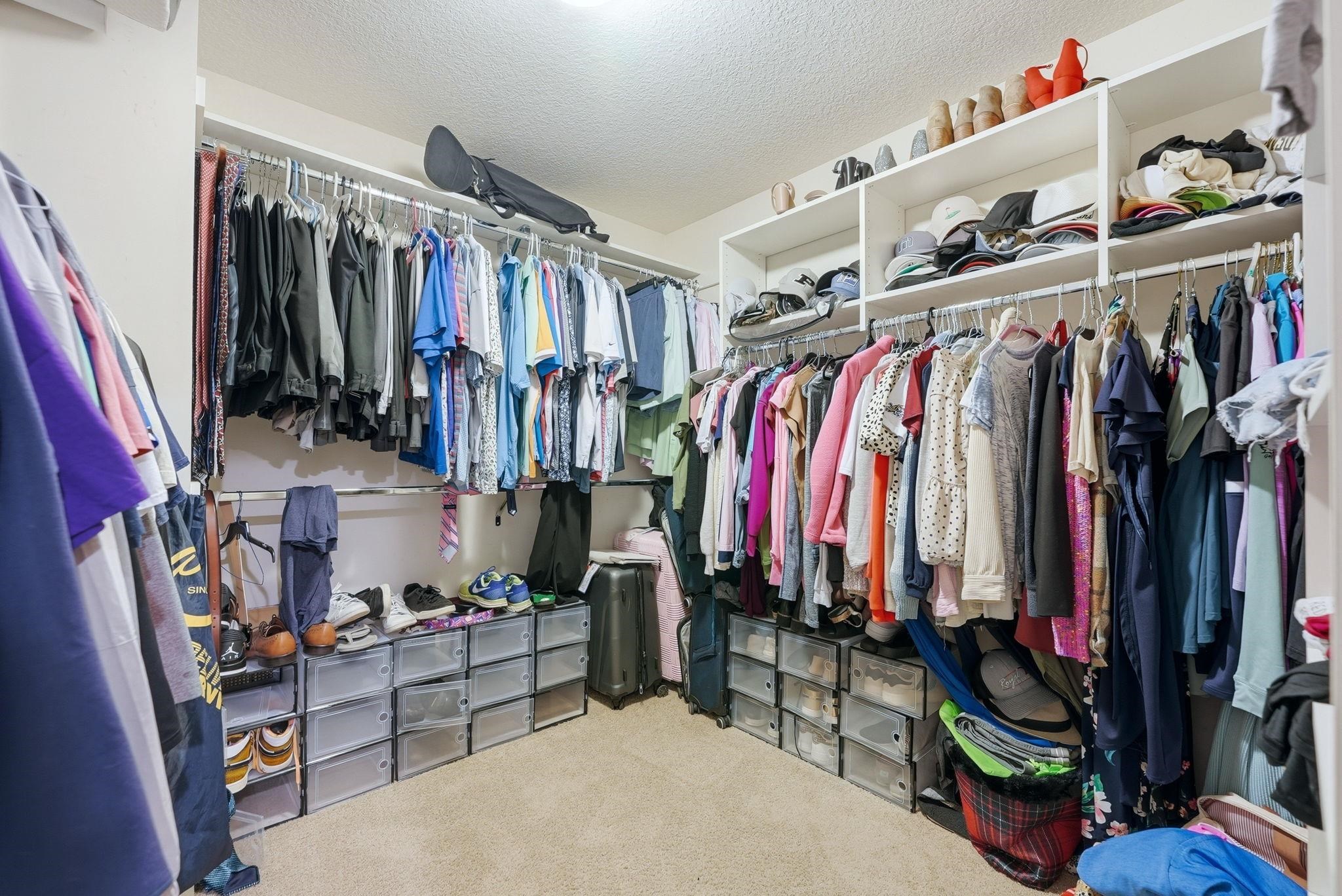 Walk-in closet featuring extensive built-in shelving and hanging rods