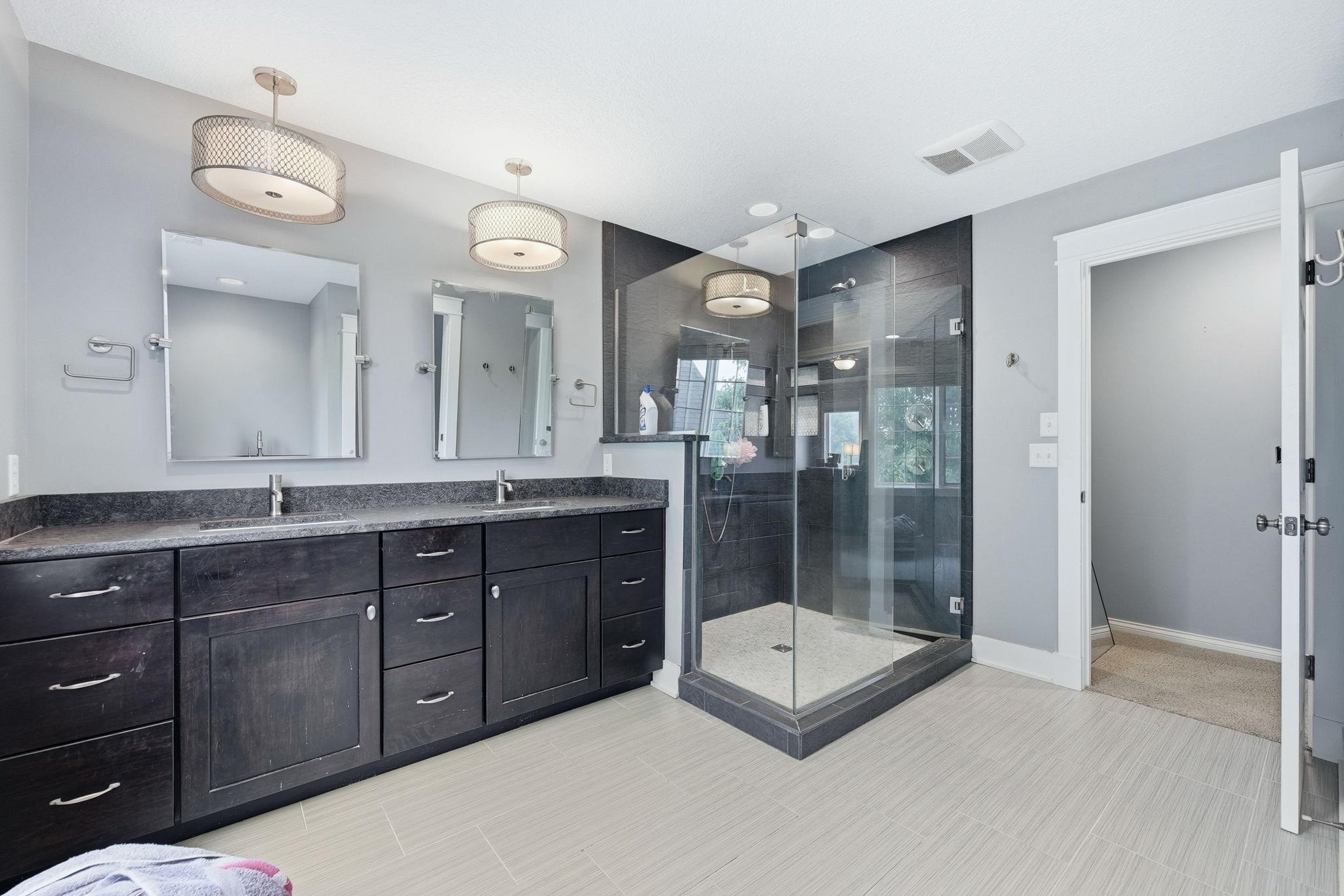 Double vanity with dark wood cabinetry and dual sinks, complemented by contemporary pendant lighting
