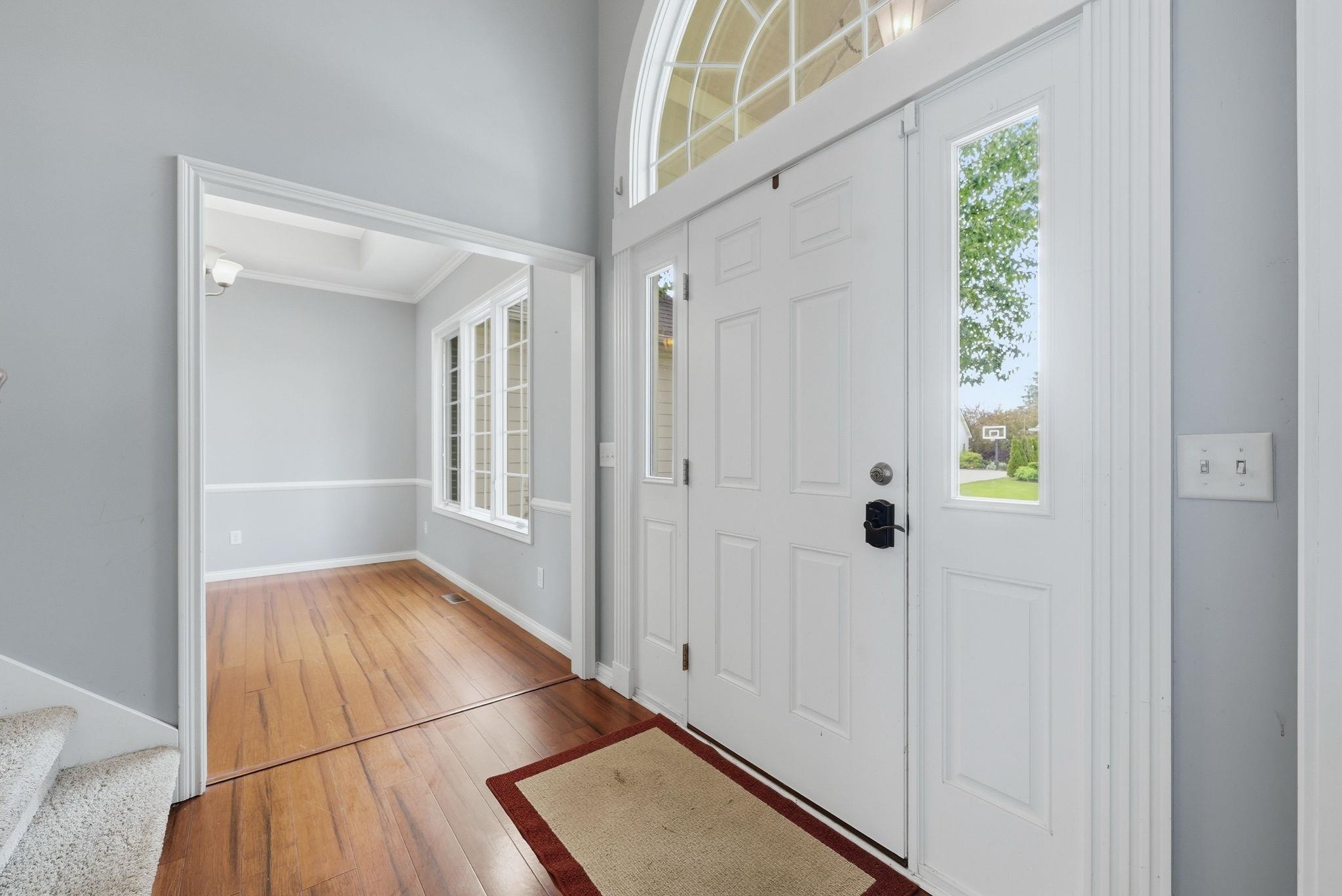 Entryway featuring a double door with sidelight, arched transom window, and light wood-finish flooring