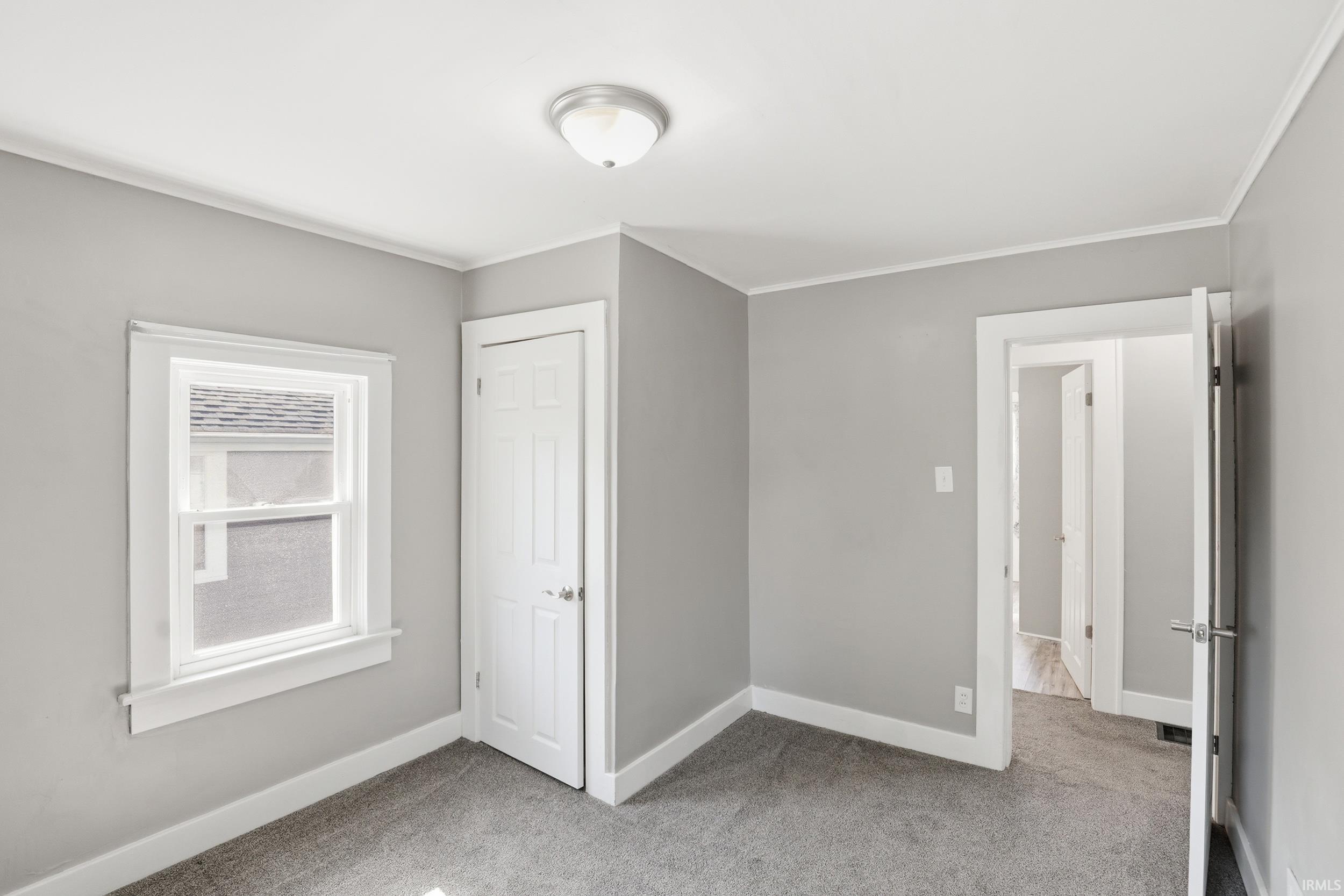 Neutral wall tones complementing white trim, a double-hung window, and a paneled closet door