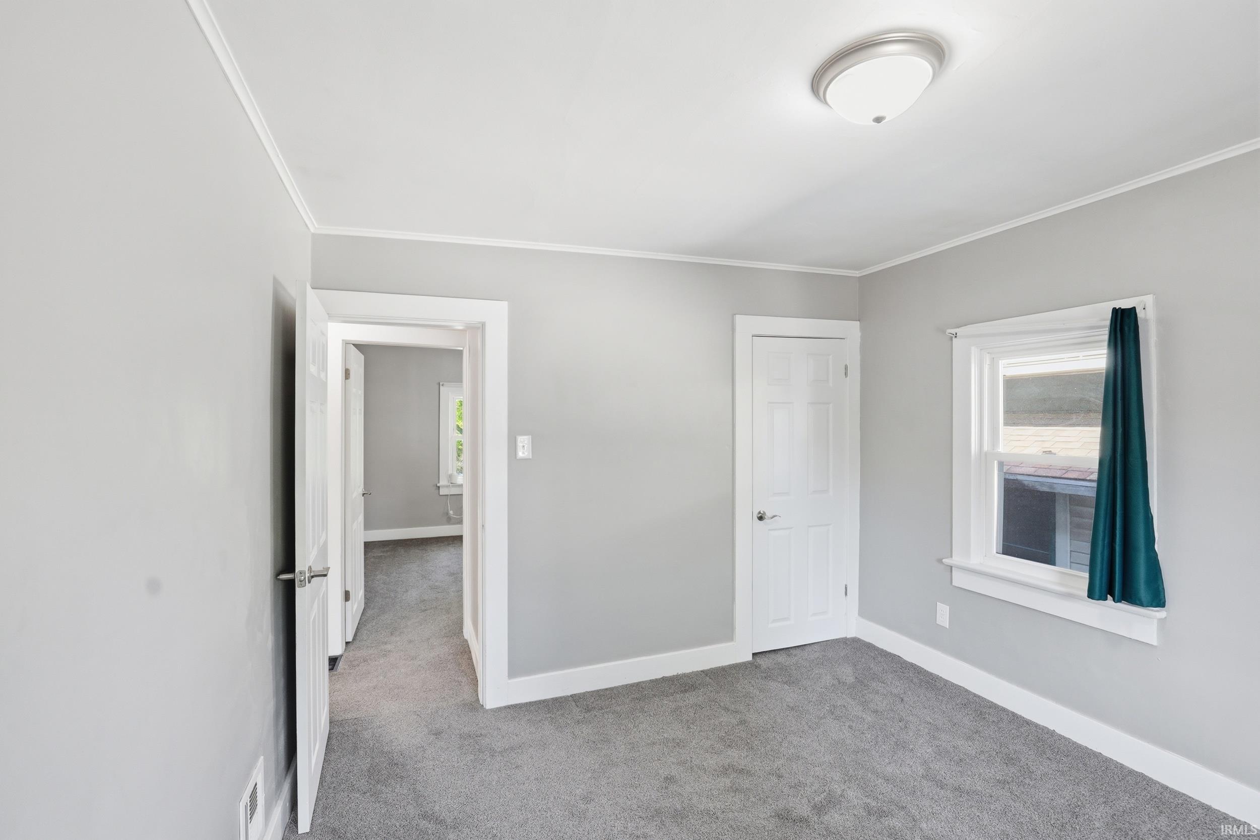 Room with light gray walls, gray carpet, white trim, and a semi-flush mount ceiling light