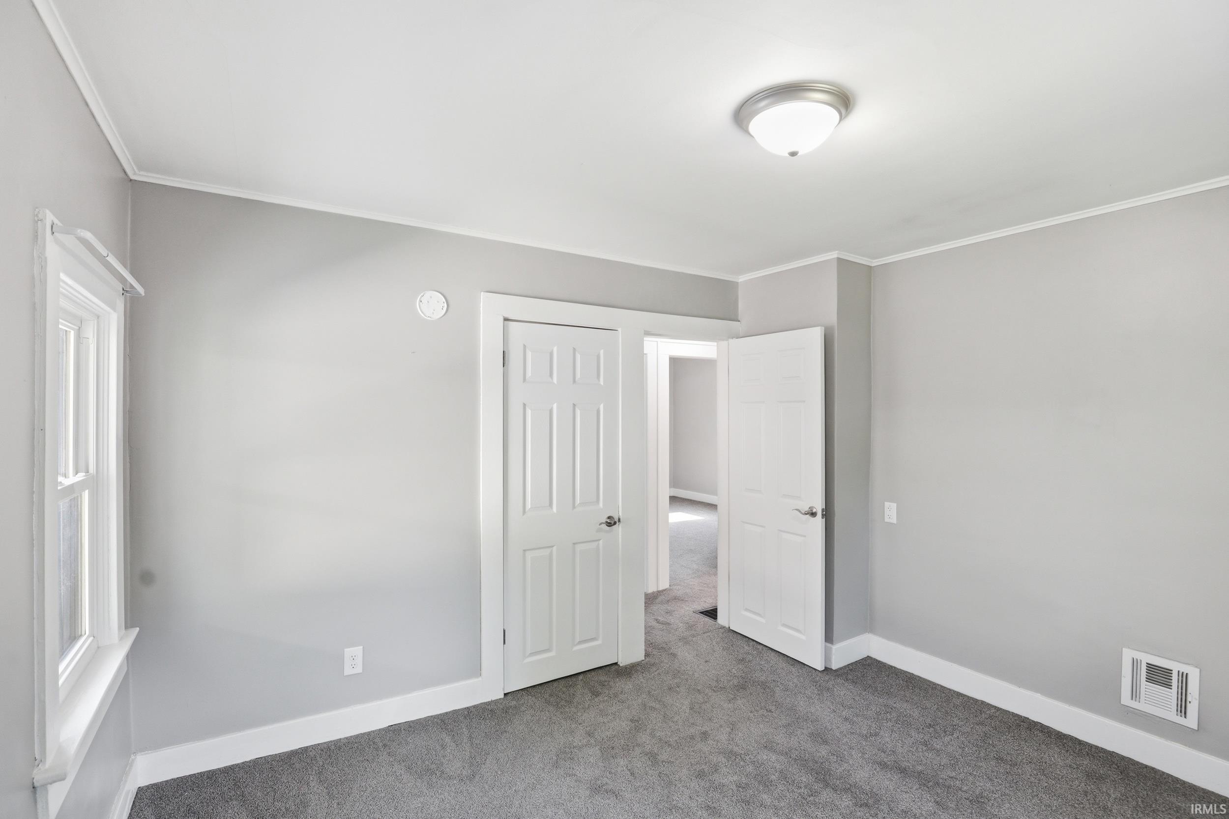 Bedroom featuring light gray wall paint, white trim, gray carpet, a flush-mount ceiling light, and white paneled doors